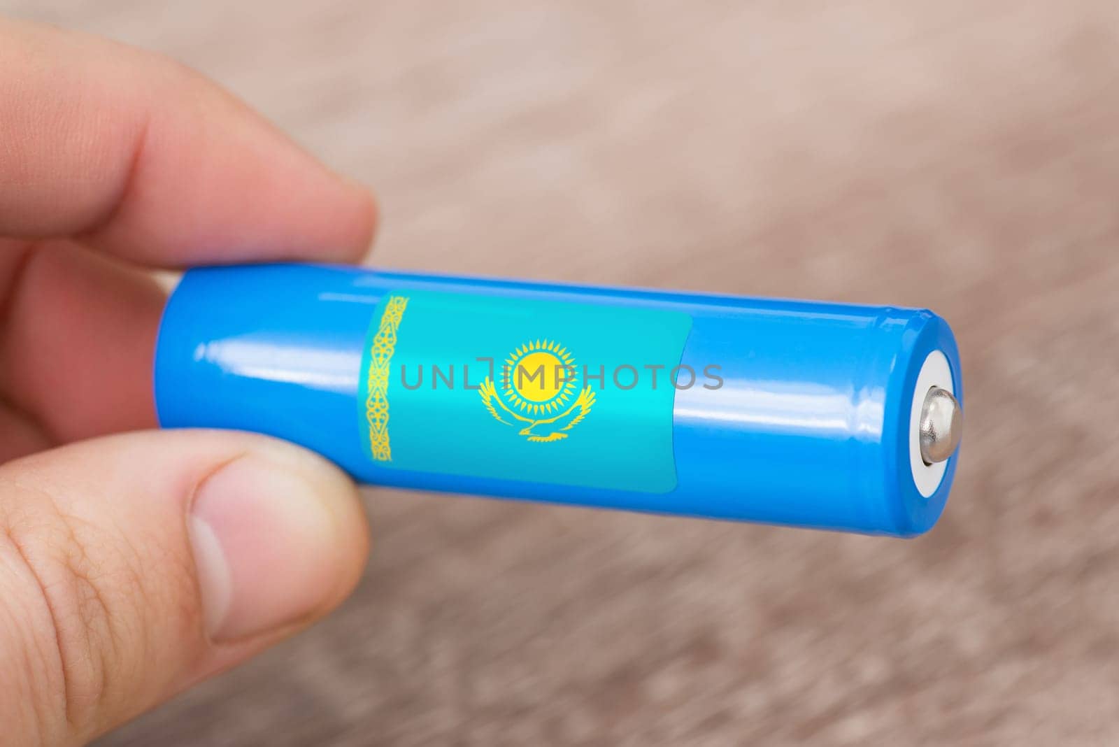 Rechargeable li-ion battery in hand of a man with sticker of Kazakhstan flag by VitaliiPetrushenko