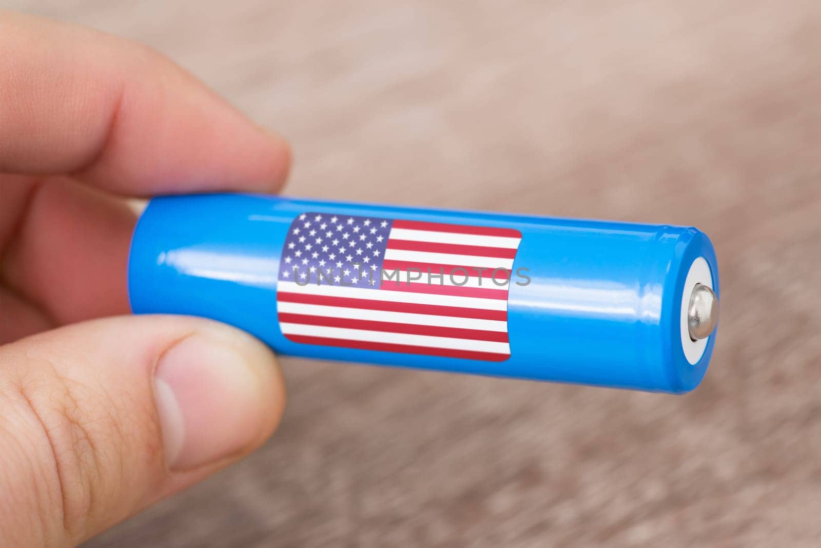 Rechargeable li-ion battery in hand of a man with sticker of USA flag by VitaliiPetrushenko