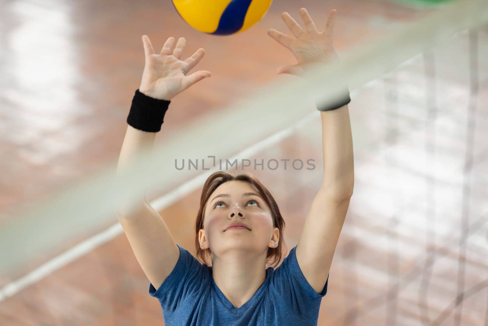 Girl setting the ball near net on volleyball court