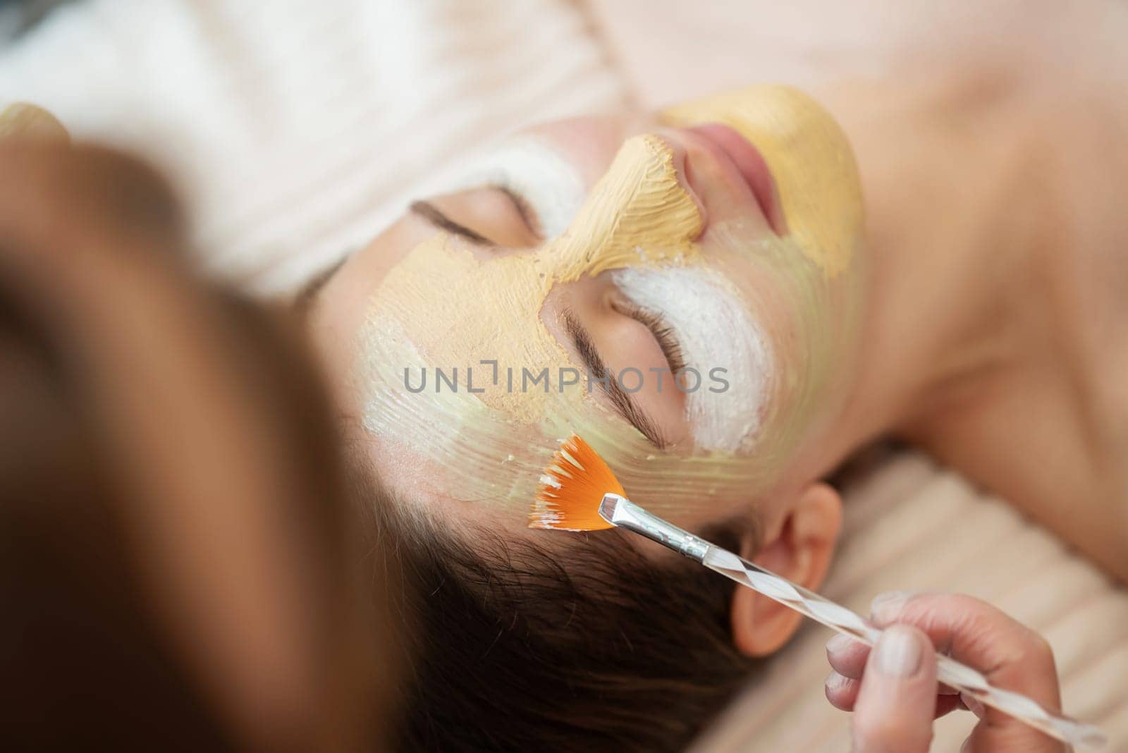 Female cosmetologist applying masks of different types on the face of young girl client by VitaliiPetrushenko