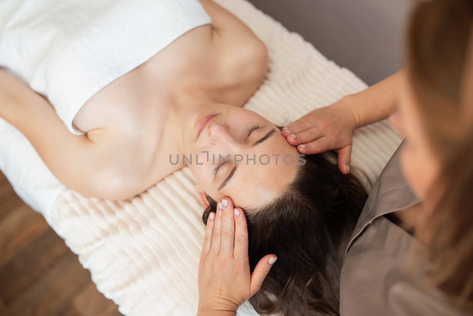 View from above of a cosmetologist making a facial massage for female client by VitaliiPetrushenko
