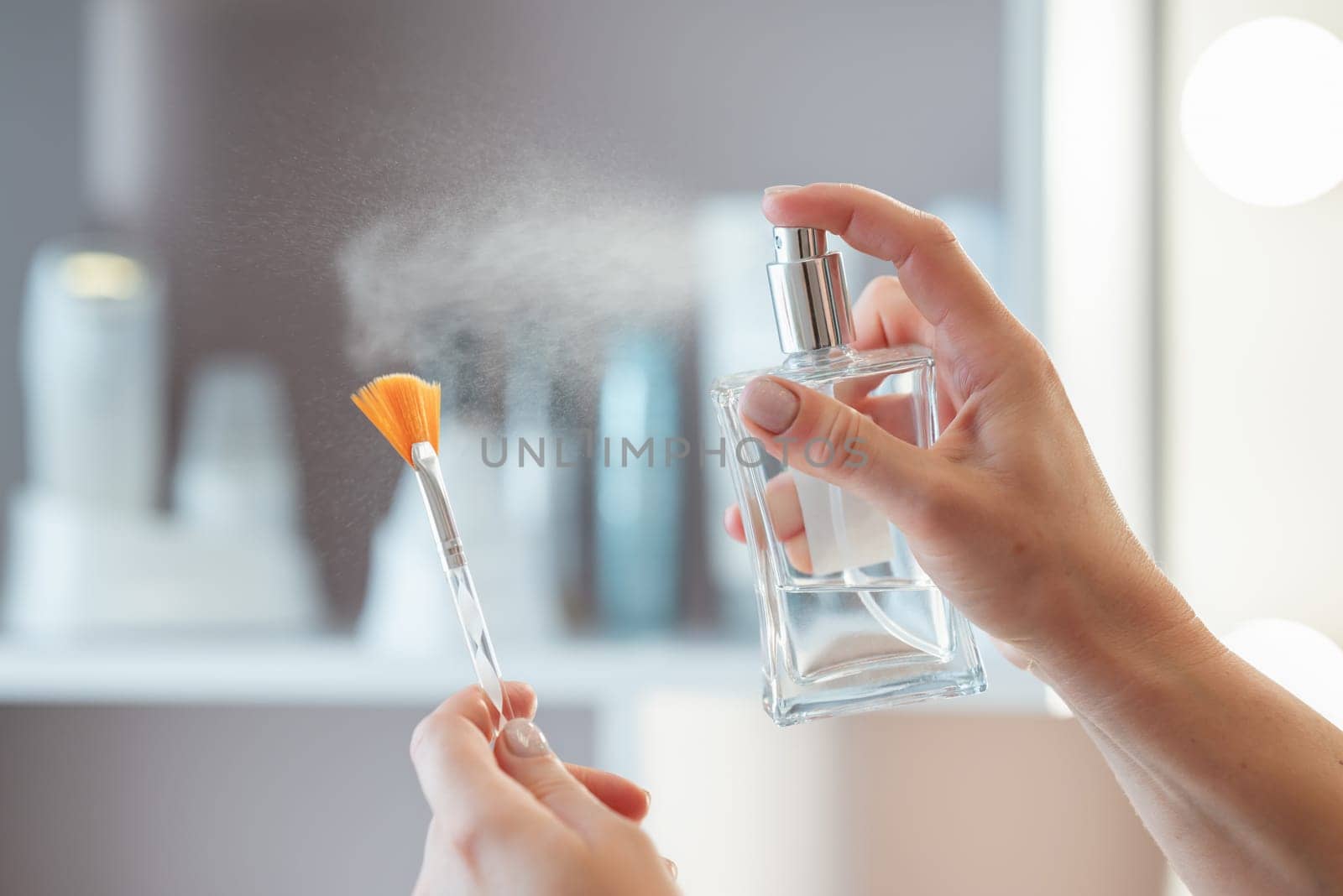 Close up of female hands holding a professional cosmetic brush and sprinkling it with an antiseptic by VitaliiPetrushenko