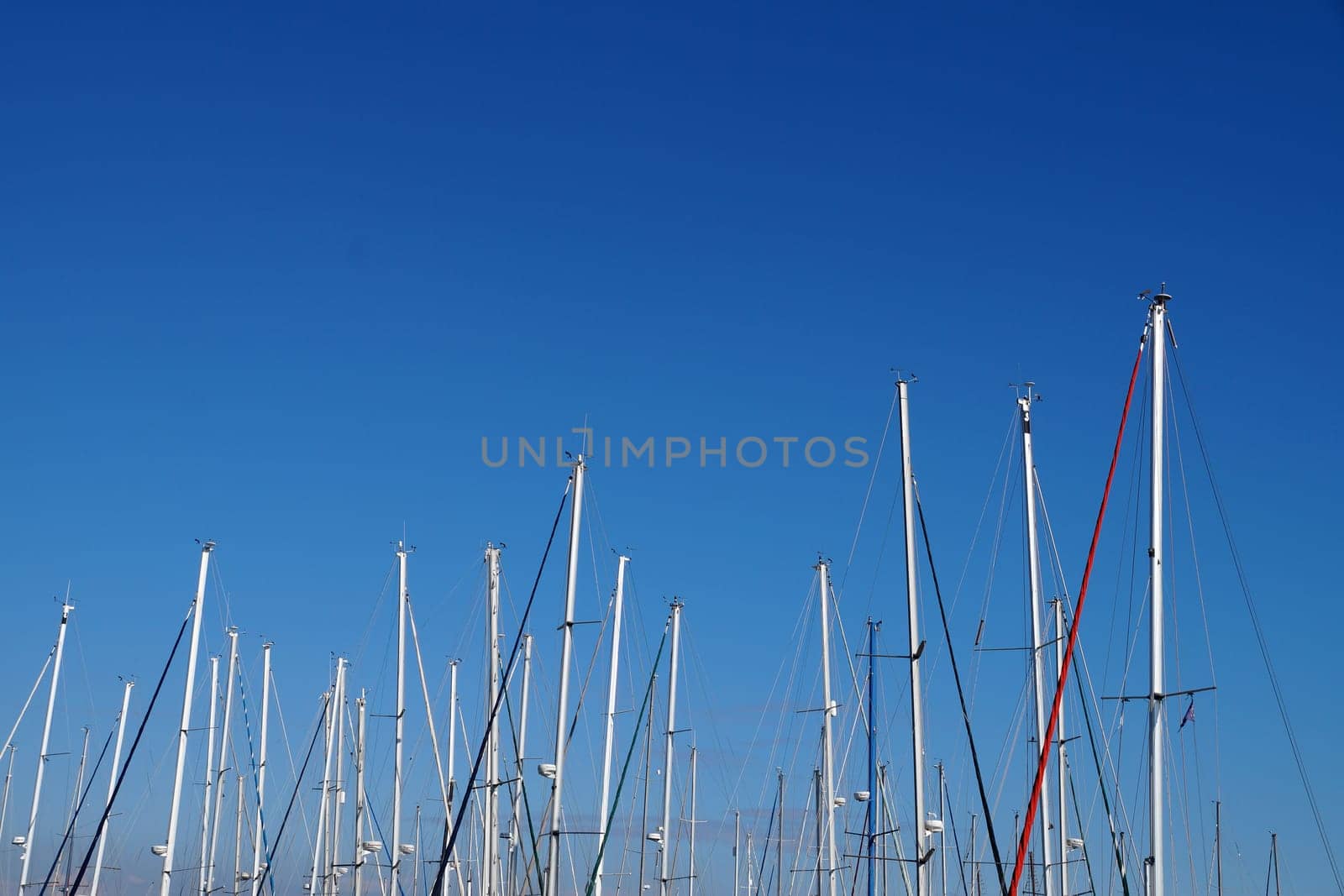 Yacht masts without sails against the background of a clear blue sky, copy space by Annado