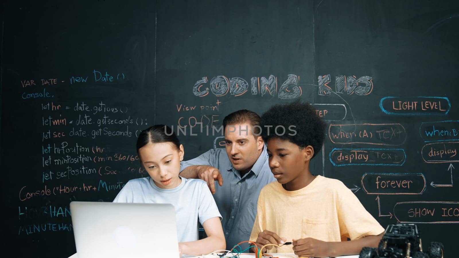 Caucasian teacher pointing at laptop while teaching about engineering code. Instructor working by using laptop while happy highschool student learning and studying programing system. Edification.