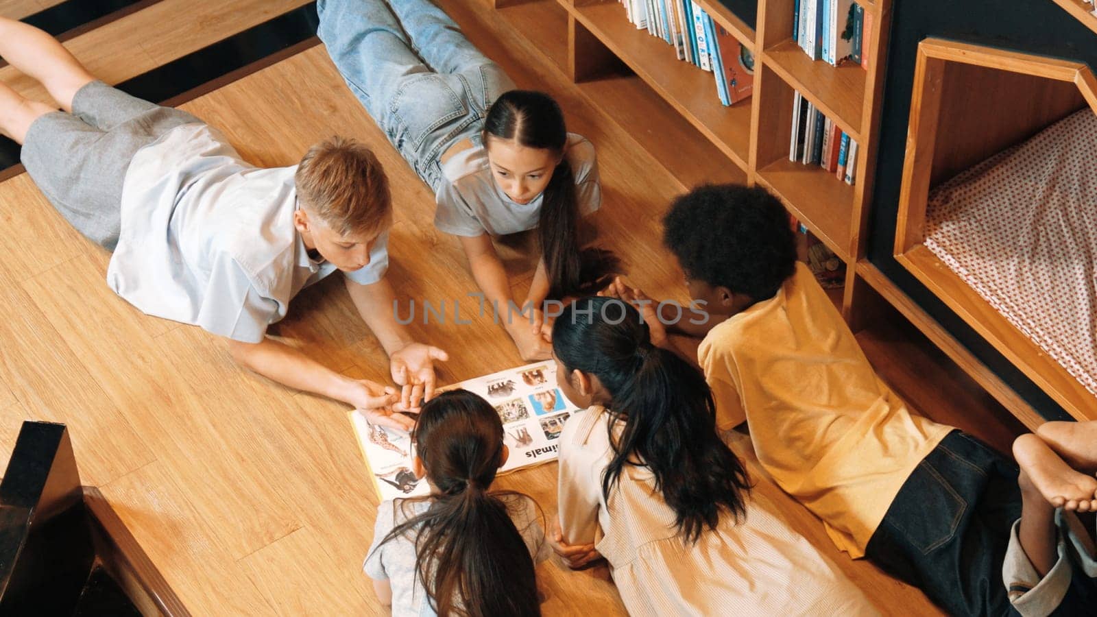 Group of children lying down in a circle while reading a book. Edification. by biancoblue