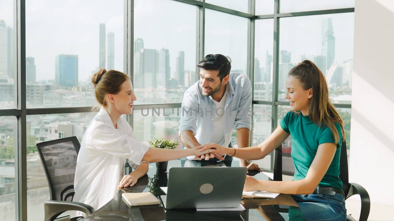 Professional business team receive a good news by using laptop while celebrate their success. Project manager high five and clap hands in front of laptop with colleague at modern office. Tracery