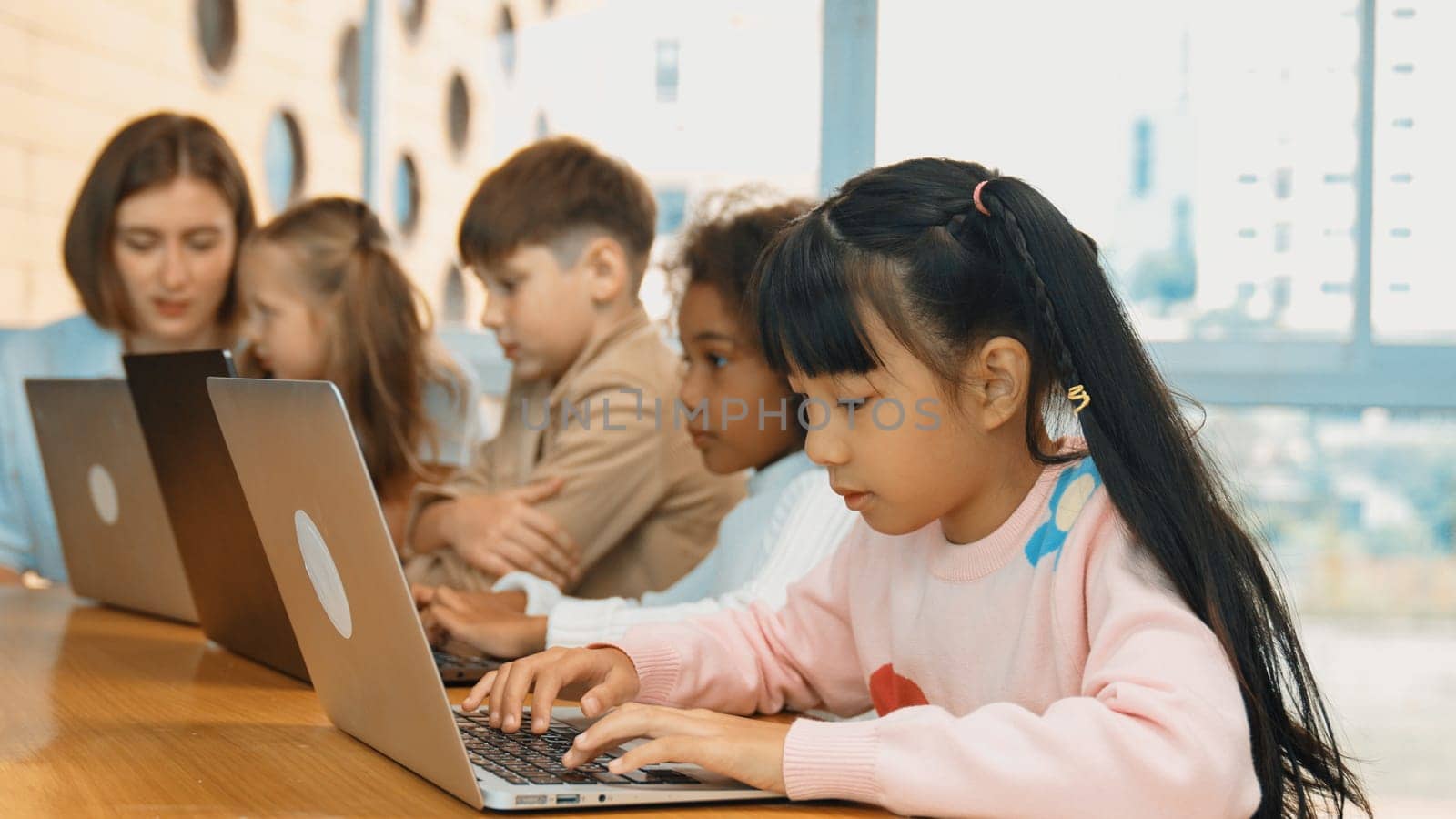 Smart asian girl working on laptop and turn head to doing ok or okay at camera. Diverse children coding or programing engineering code or prompt by using computer in STEM technology class. Erudition.