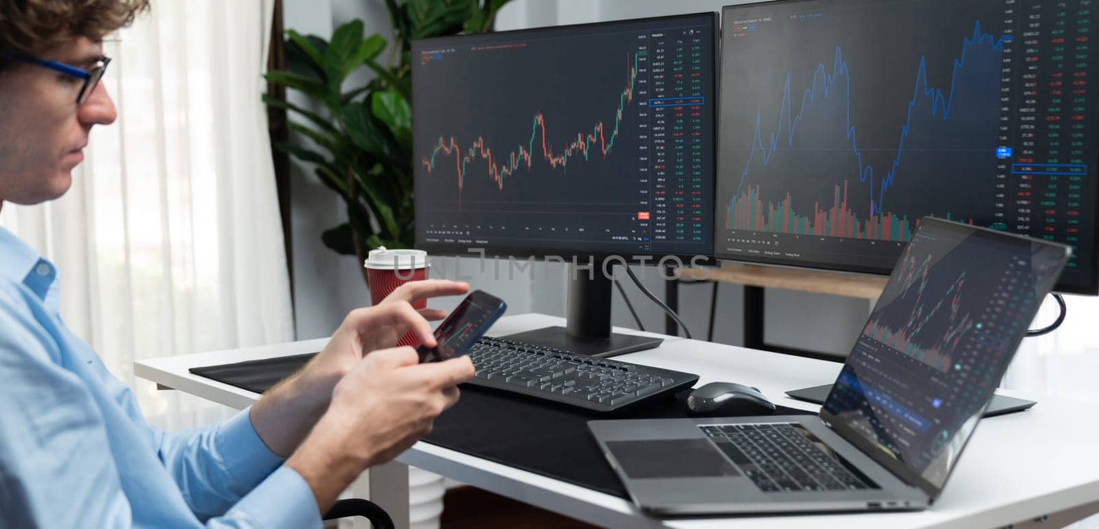 Young investor in stock trader looking on smartphone of dynamic financial exchange investment surrounded current market graph screen in real time at modern office, analyzing statistic profit. Gusher.