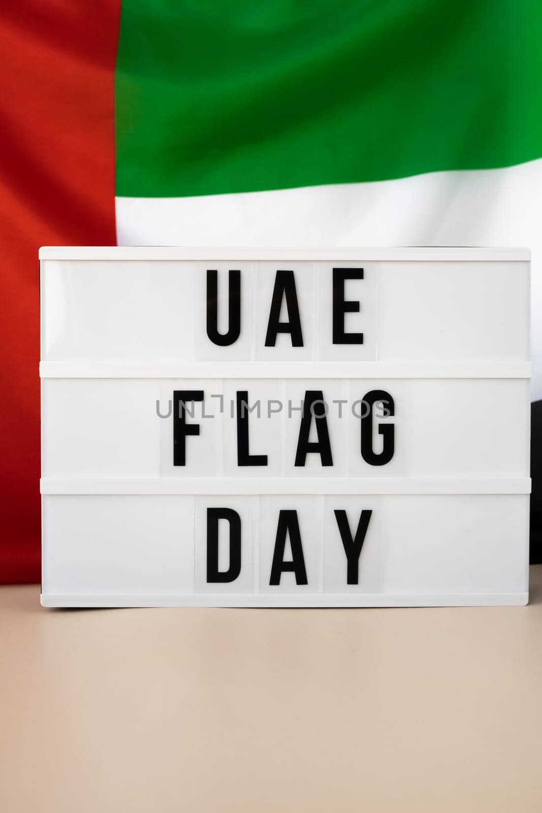 Lightbox with text UAE FLAG DAY on United Arab Emirates waving flag made from silk material. Independence Commemoration Day Muslim Public holiday celebration background. The National Flag of UAE. Patriotism