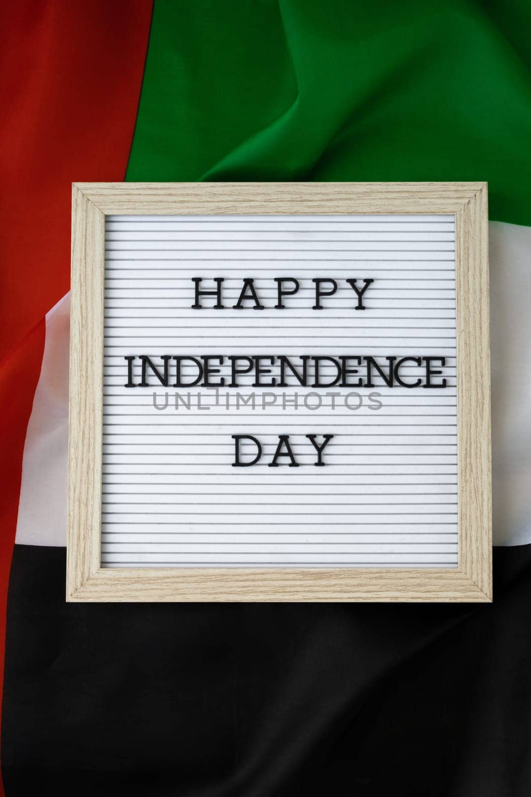 Text HAPPY INDEPENDENCE DAY on background waving flag of UAE. National holiday of United Arab Emirates. Commemoration Day Muslim Arabian holidays. Dubai celebration