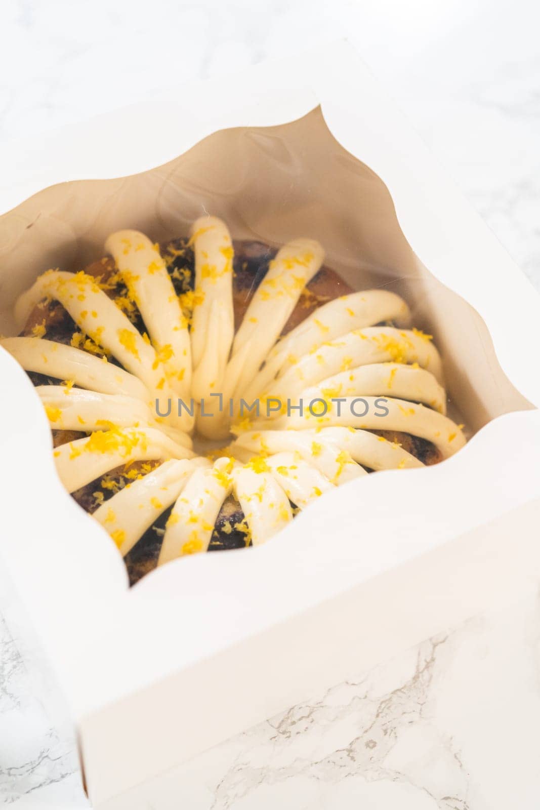 The freshly baked bundt cakes are carefully nestled into white paper boxes, preparing them for secure transportation while maintaining their delectable appearance.