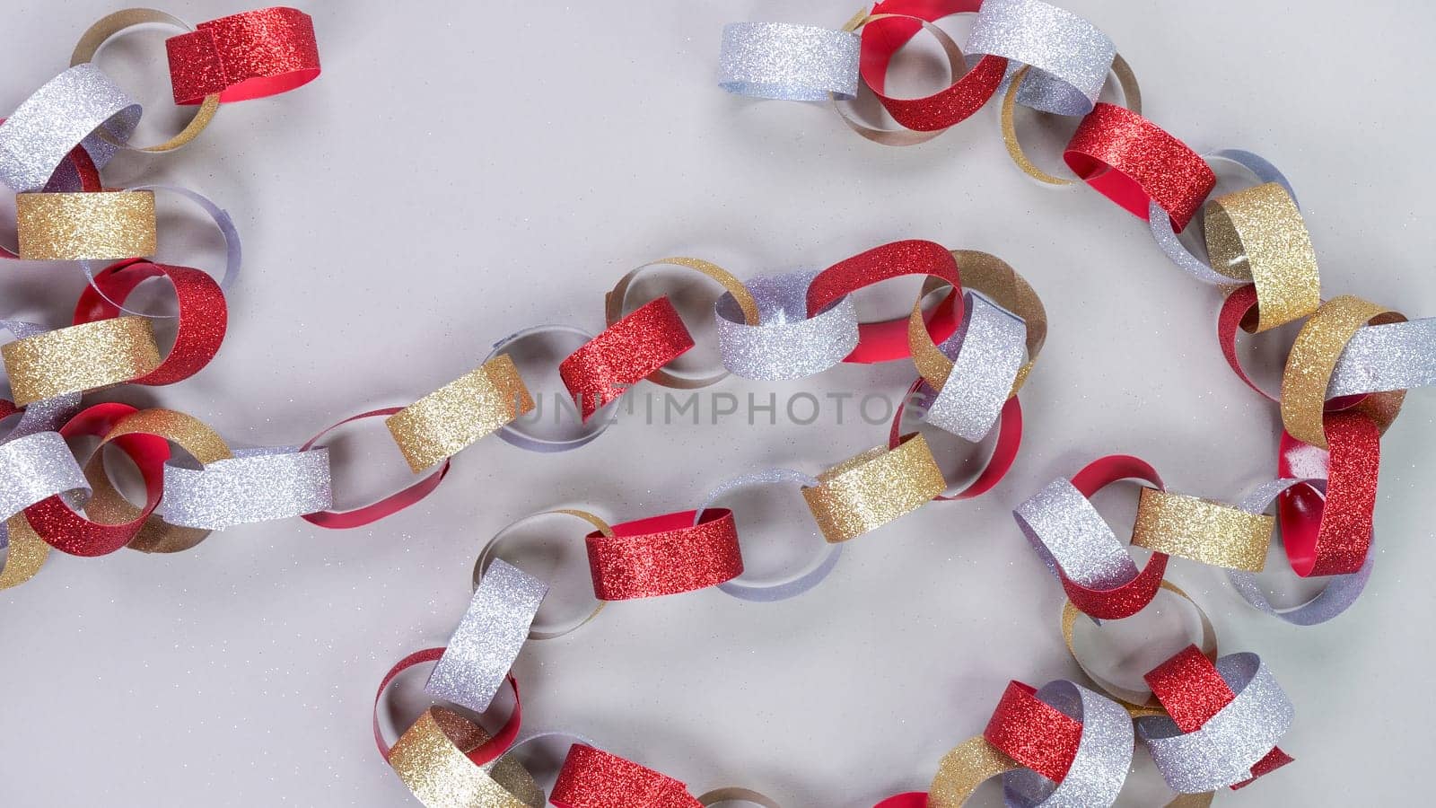 Colorful background with strips of gold silver red sparkling chain garland on grey. Festive Christmas birthday decoration garland.Space for text