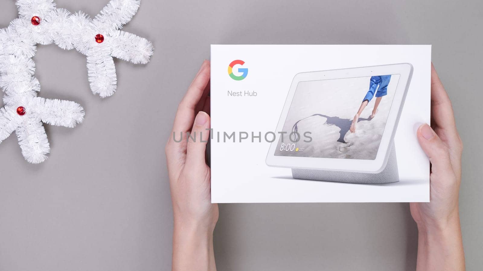 Hands holding gift box of Google Nest Hub on the grey background. Birthday gift. Space for text. Gatineau, QC Canada - Dec 21, 2022. by JuliaDorian