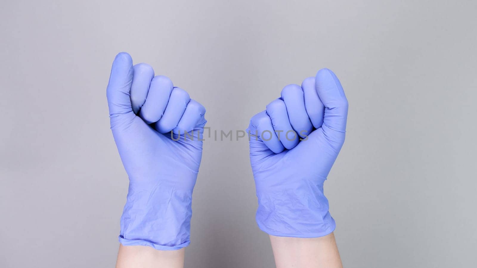 Hands in blue gloves of doctor or nurse over grey background with copy space. Medical gloves. by JuliaDorian
