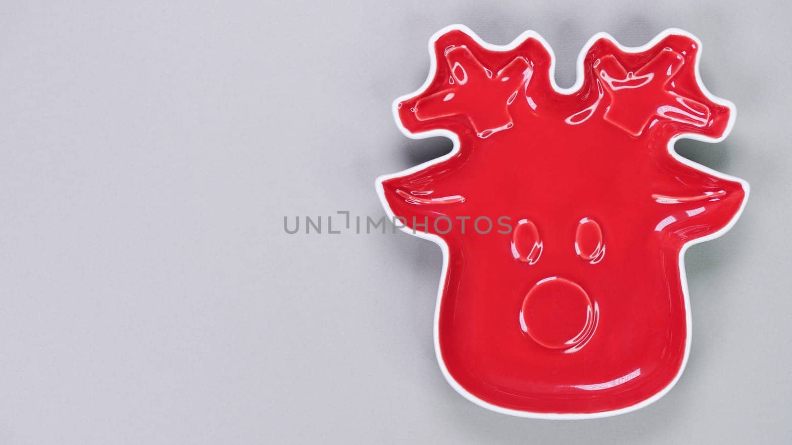 Festive table setting with red plate in Christmas raindeer shape on grey background. Holiday table decoration Top view. Space for text