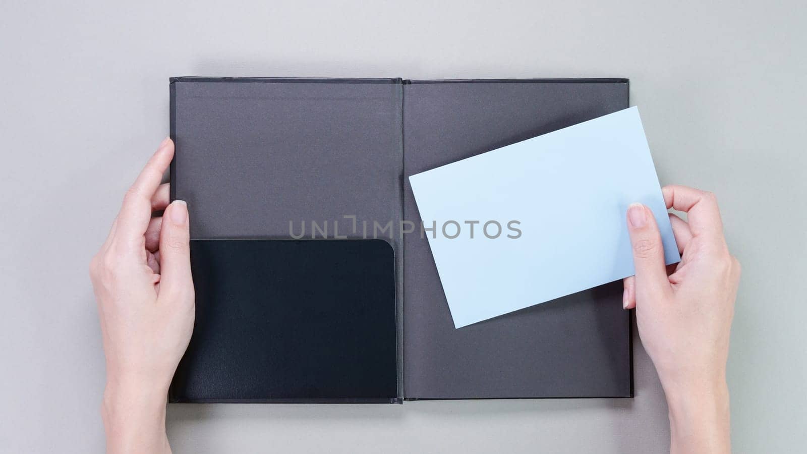 Blue mockup envelop with empty space for text and design in hand of young woman on grey background. Board, blank, template, mockup, gift, book, greeting card, layout for a slogan