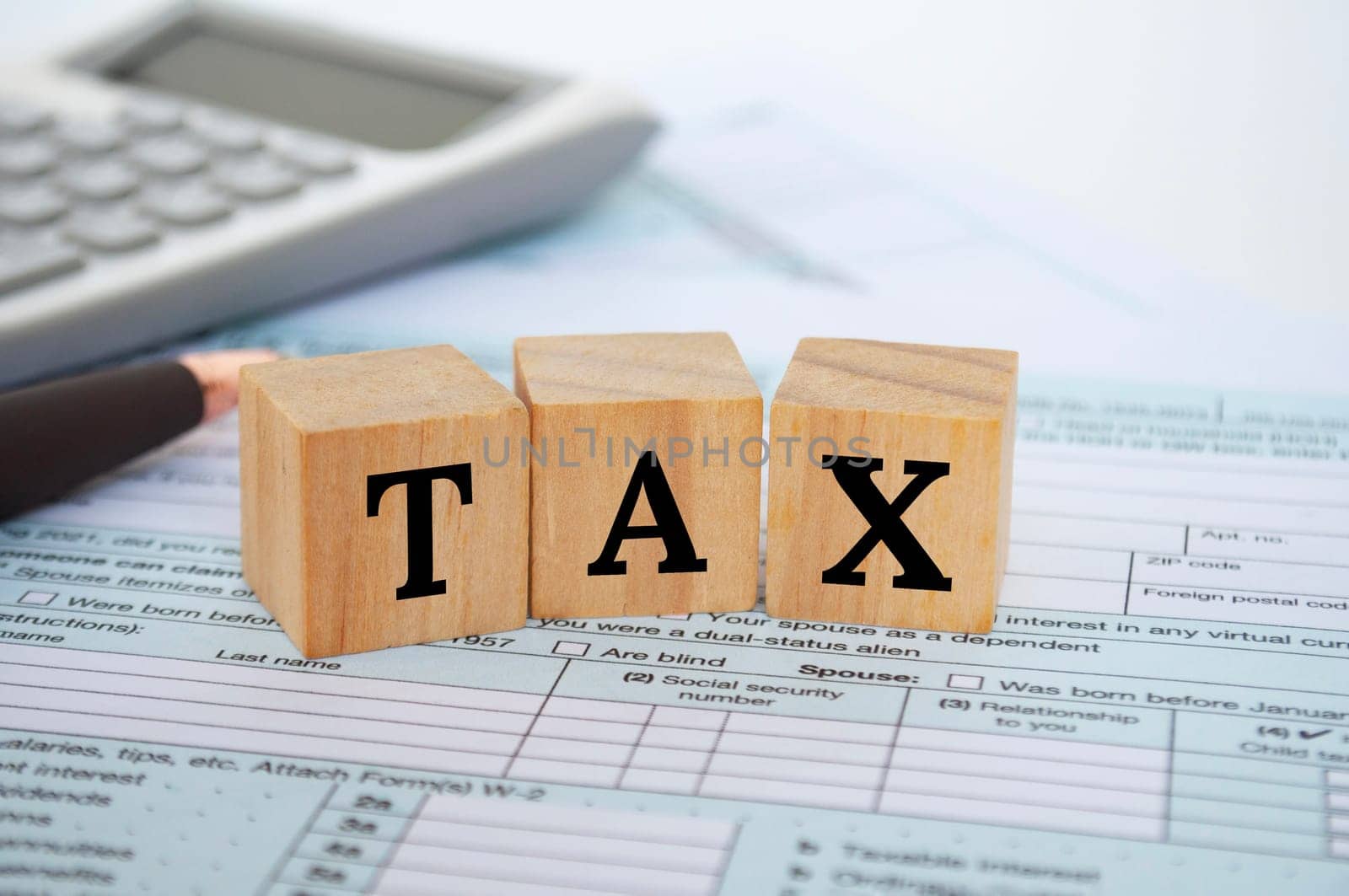 Tax wordings on wooden cubes with tax form and calculator background. Taxation concept.