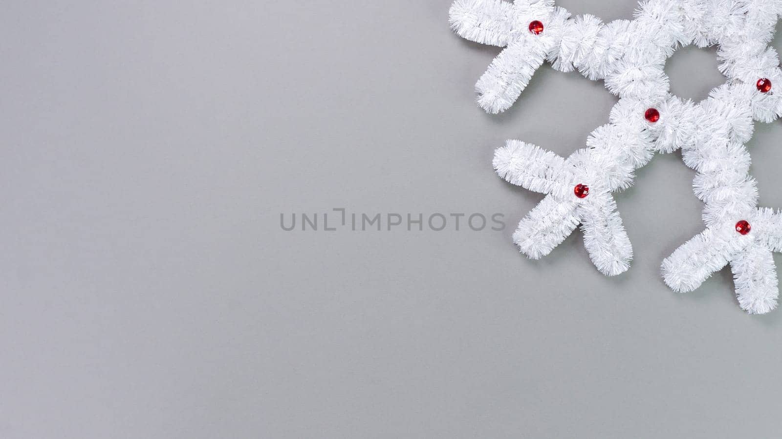 Fluffy white snowflake Christmas decor on a gray background. The concept of New Year and Christmas holidays, congratulations. Copy space. View from above.