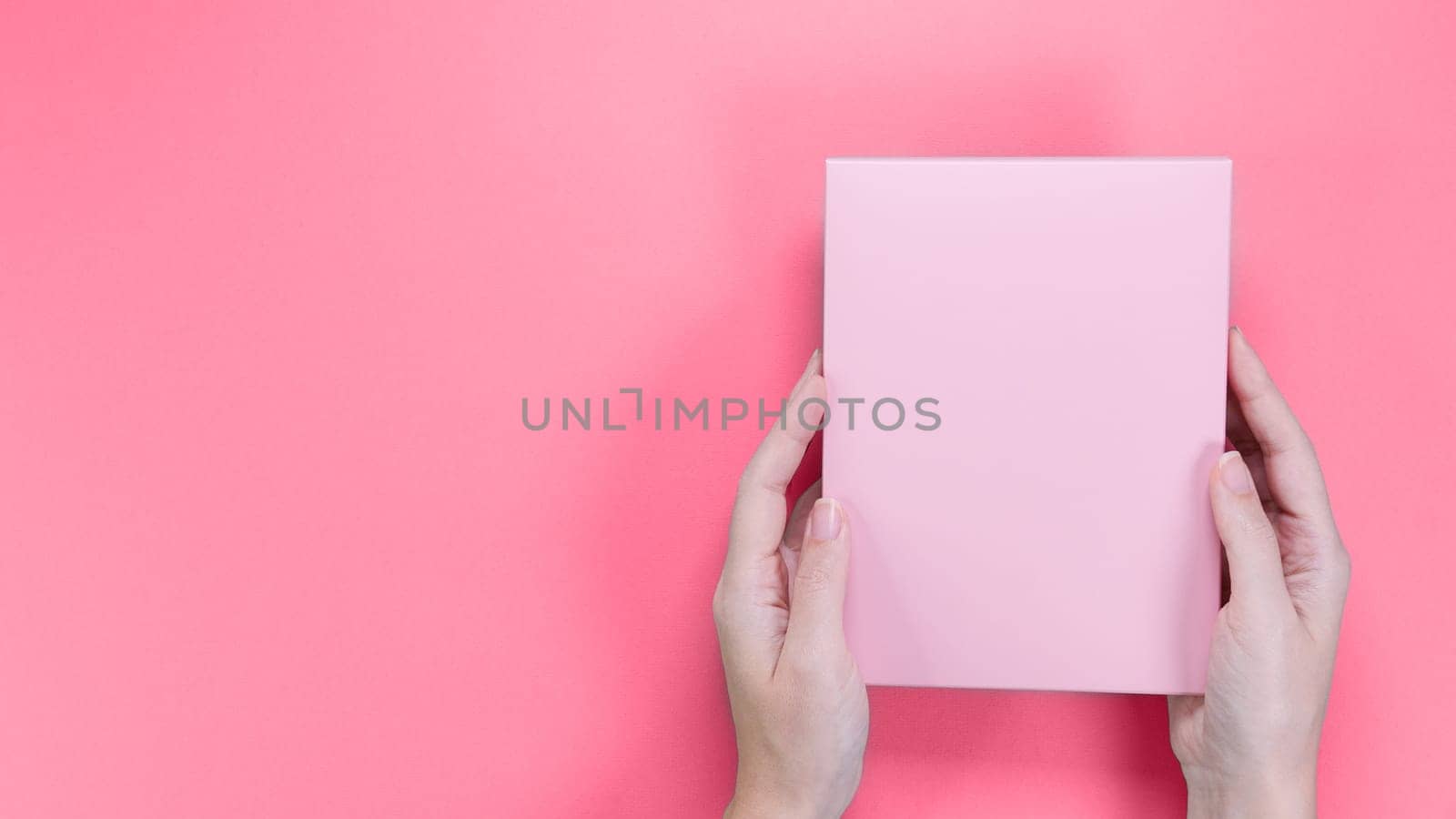 A square pink box with an copy empty space for text and design in hand of young woman in on a pink background. Color of year 2023 Viva Magenta. Board, blank, template, mockup, layout for a slogan. by JuliaDorian