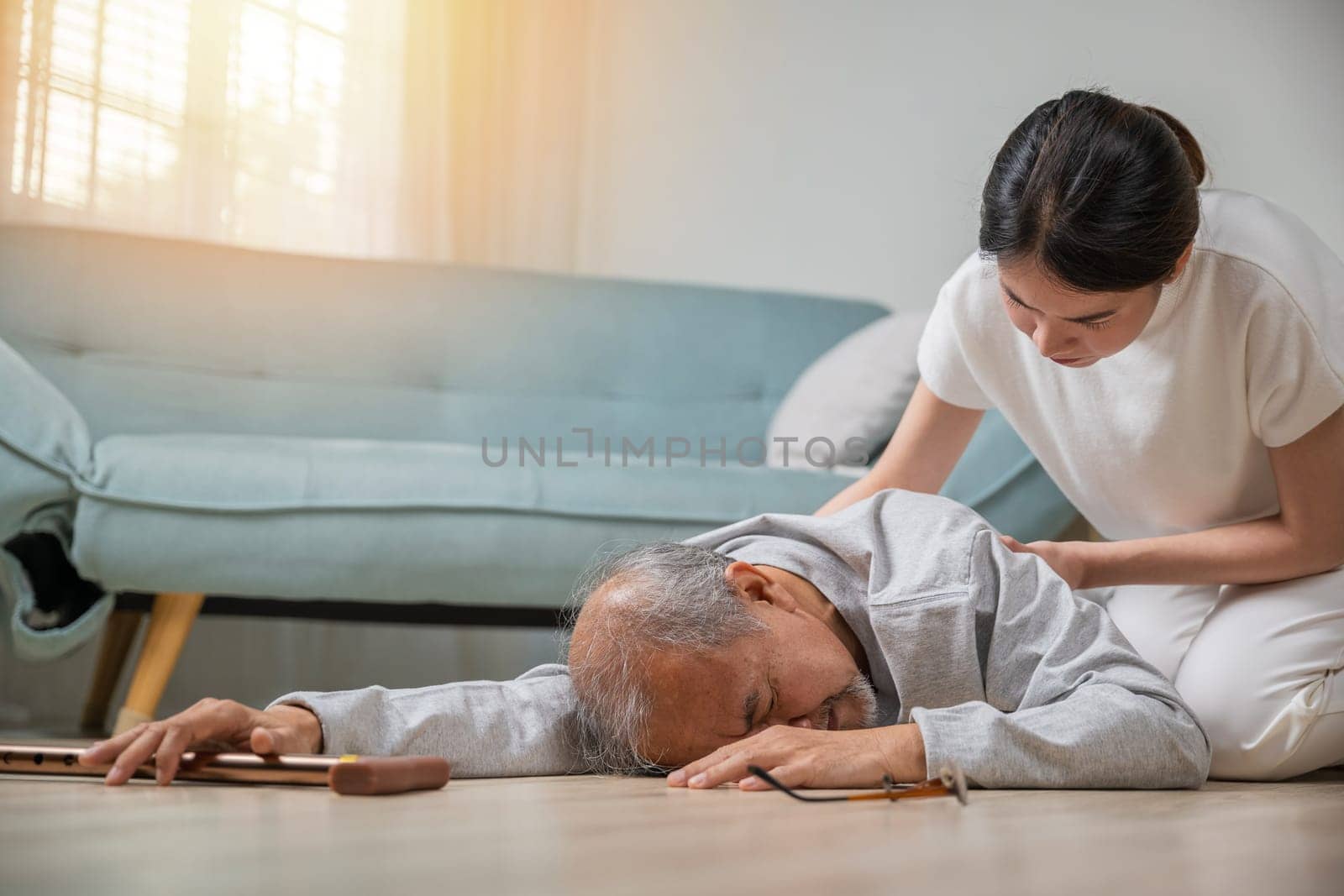 Asian elderly old man with walking stick fall on ground and granddaughter camp to help to support at home in living room, young woman halping her grandfather after falling down on floor, dizziness