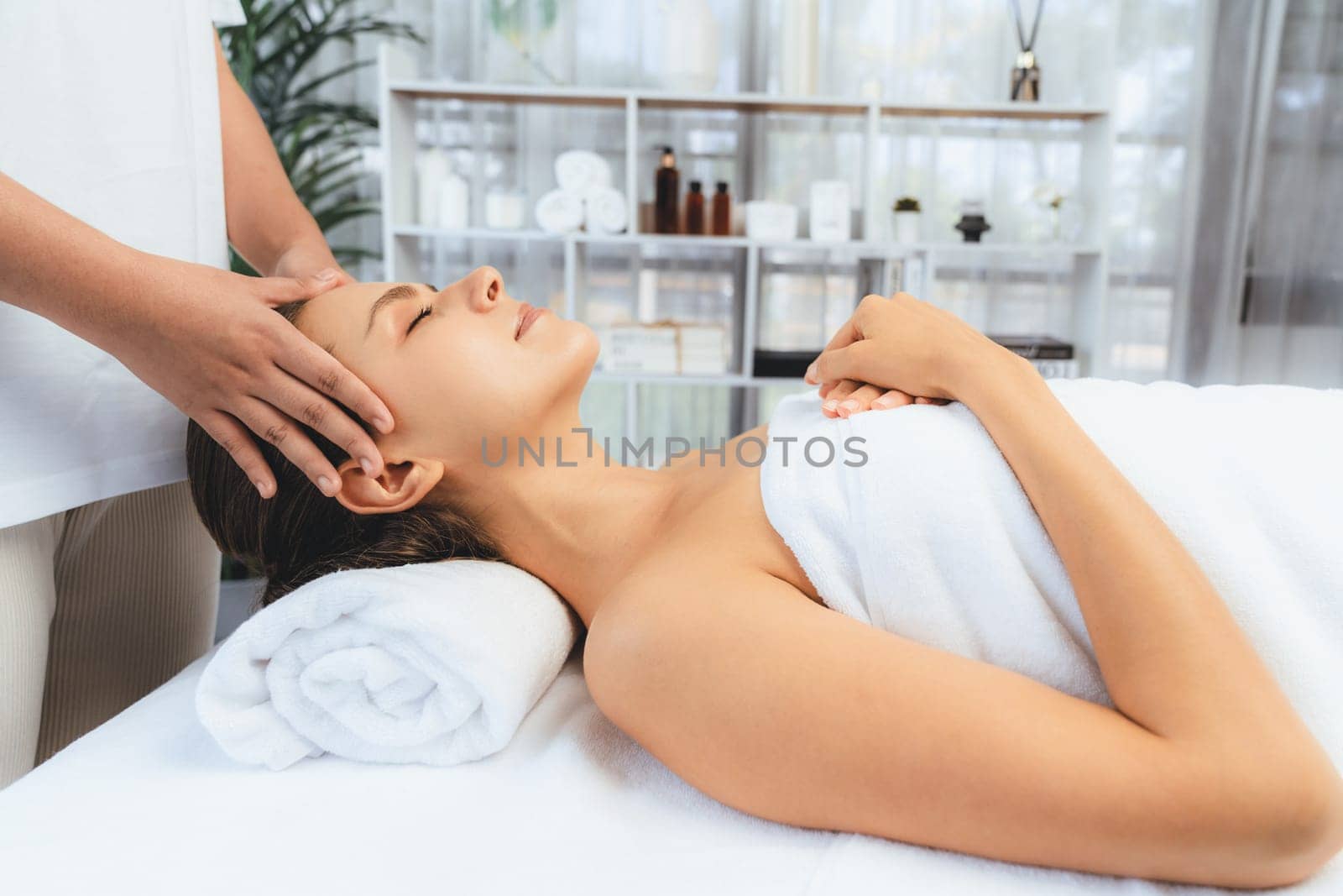 Caucasian woman enjoying relaxing anti-stress head massage and pampering facial beauty skin recreation leisure in dayspa modern light ambient at luxury resort or hotel spa salon. Quiescent