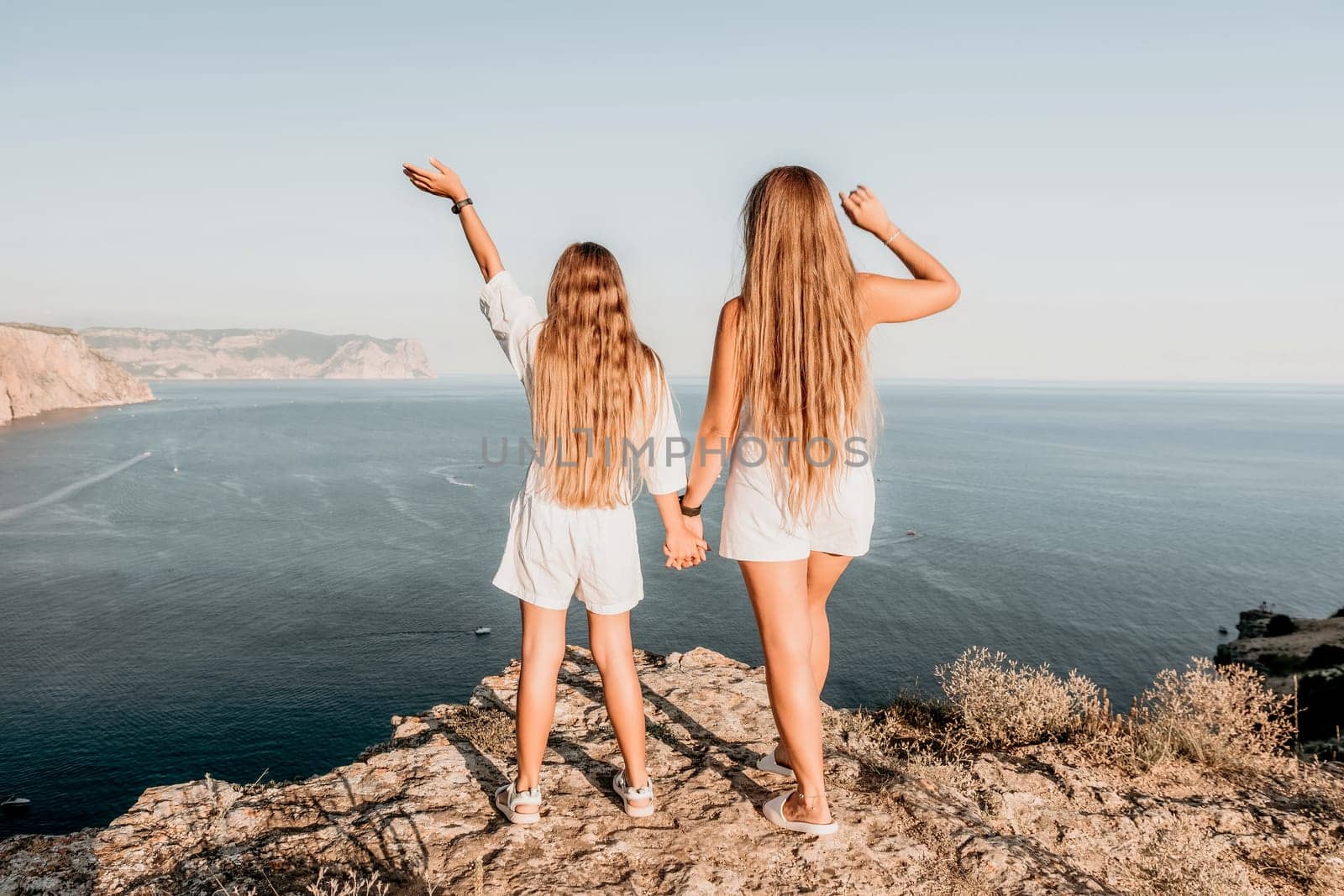 Close up portrait of mom and her teenage daughter hugging and smiling together over sunset sea view. Beautiful woman relaxing with her child.