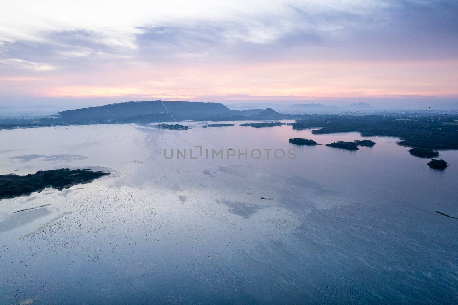 Aerial drone shot showing sunrise dawn dusk over aravalli hills lake pichola fateh sagar and cityscape in Udaipur, Chandigarh, Nainital showing famous tourist spot in India