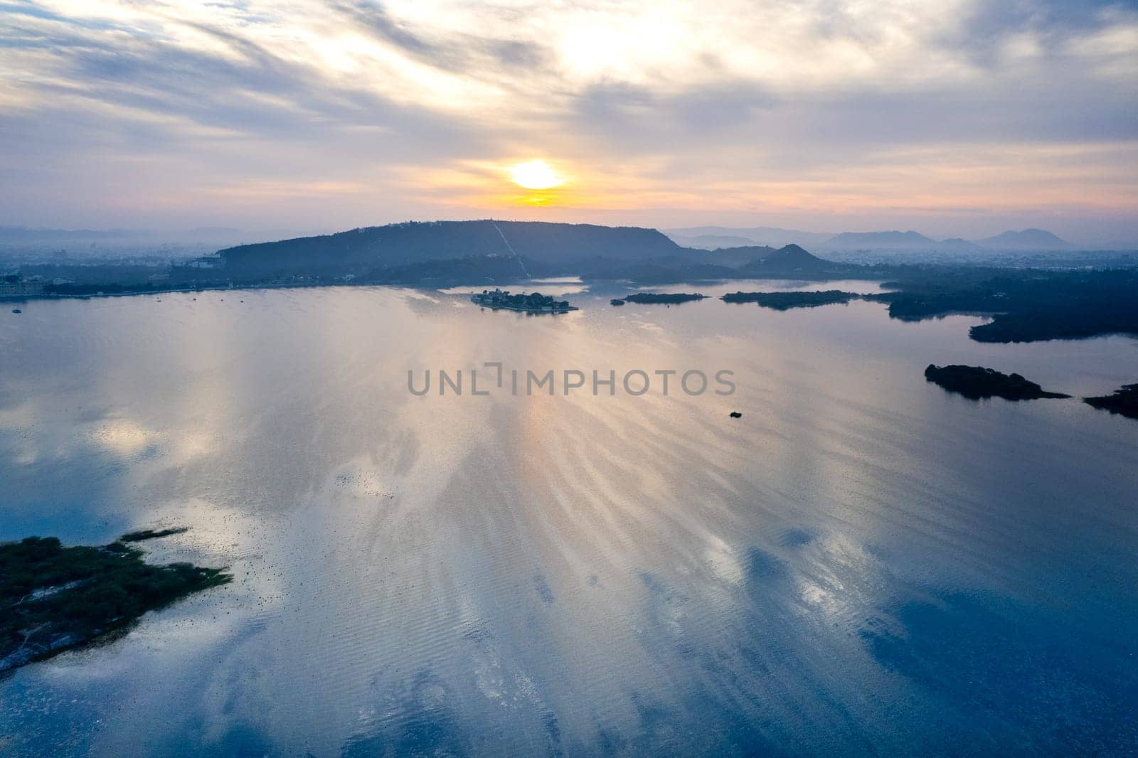 Aerial drone shot showing sunrise dawn dusk over aravalli hills lake pichola fateh sagar and cityscape in Udaipur, Chandigarh, Nainital showing famous tourist spot in India