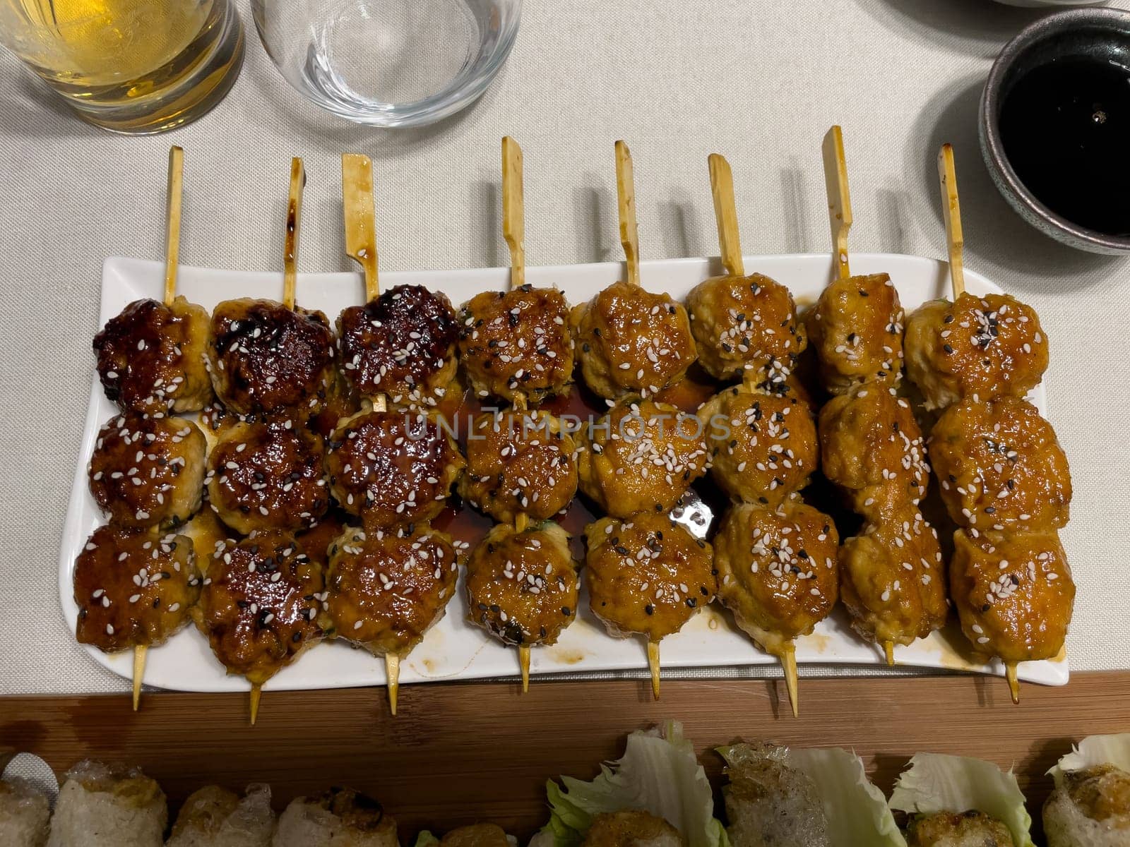 Fried beef meatballs skewers bamboo on a white plate with spicy sauce on a table, High quality photo