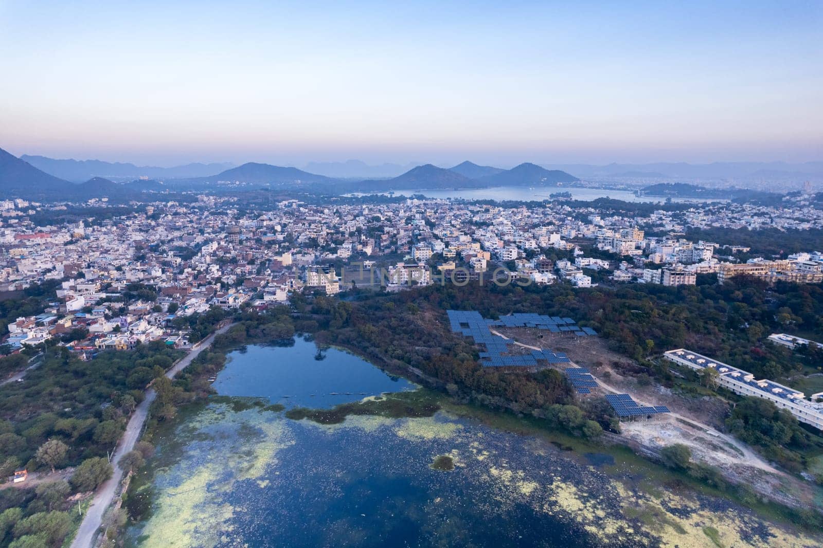 Aerial drone shot over udiapur, jaipur, kota,, cityscape with homes, houses, buildings and aravalli hills and lakes in the distance hidden in fog in India