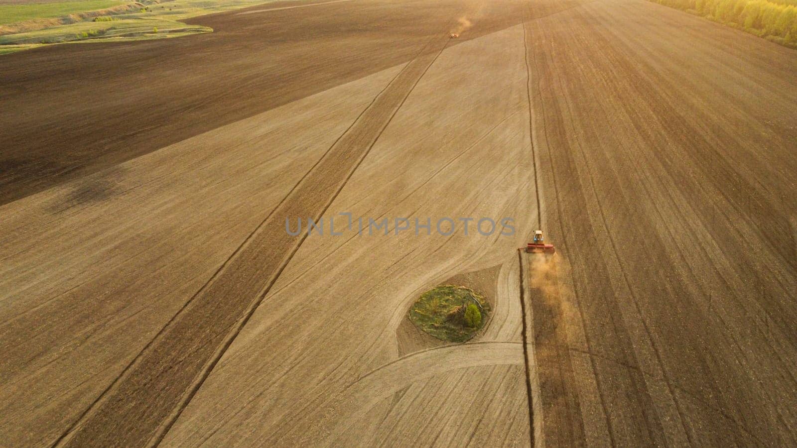 Aerial view with drone of tractor plowing the land in the countryside on the sunset.
