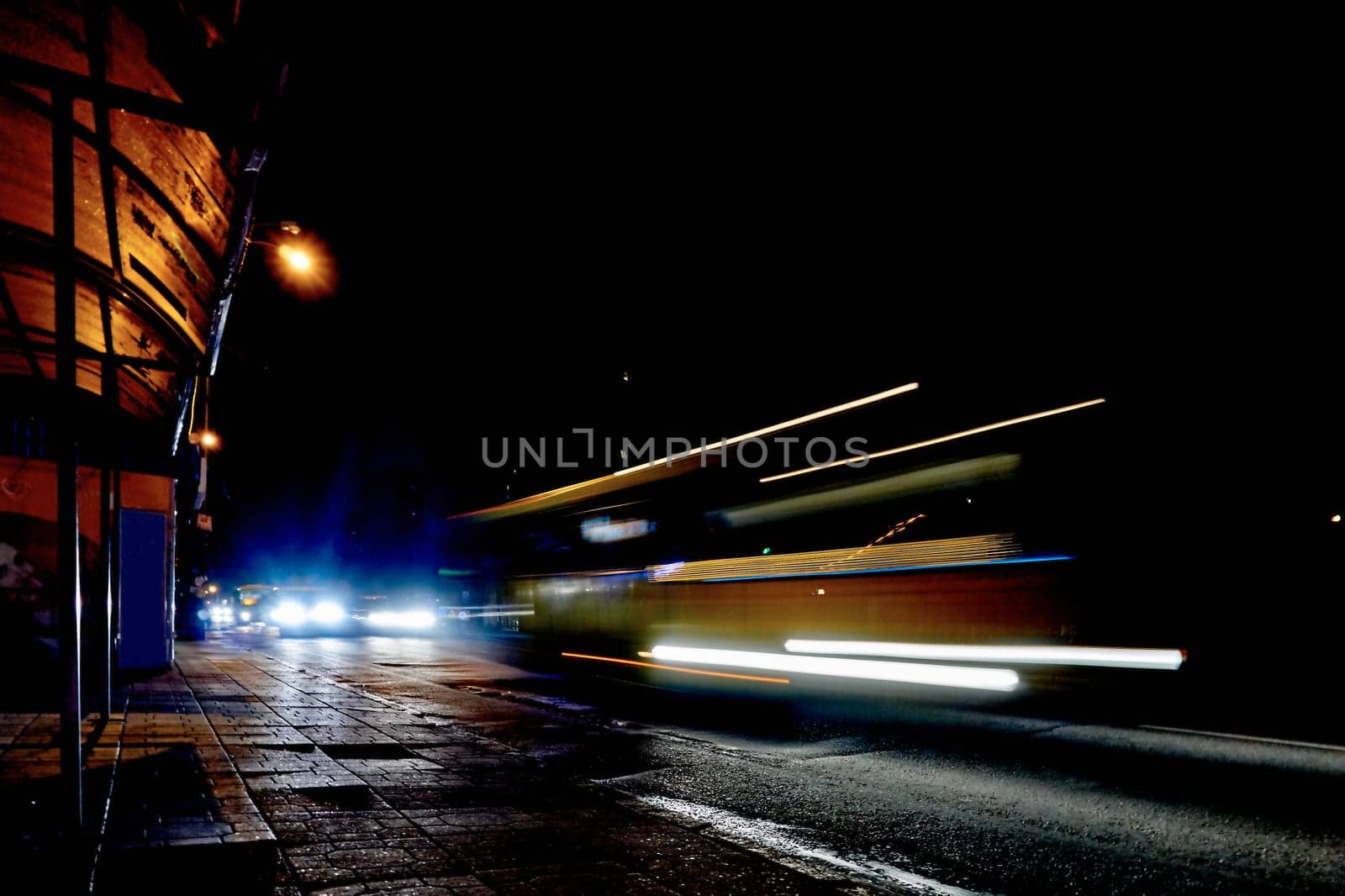 Blurred city traffic of cars on wet night street with glowing lights by jovani68