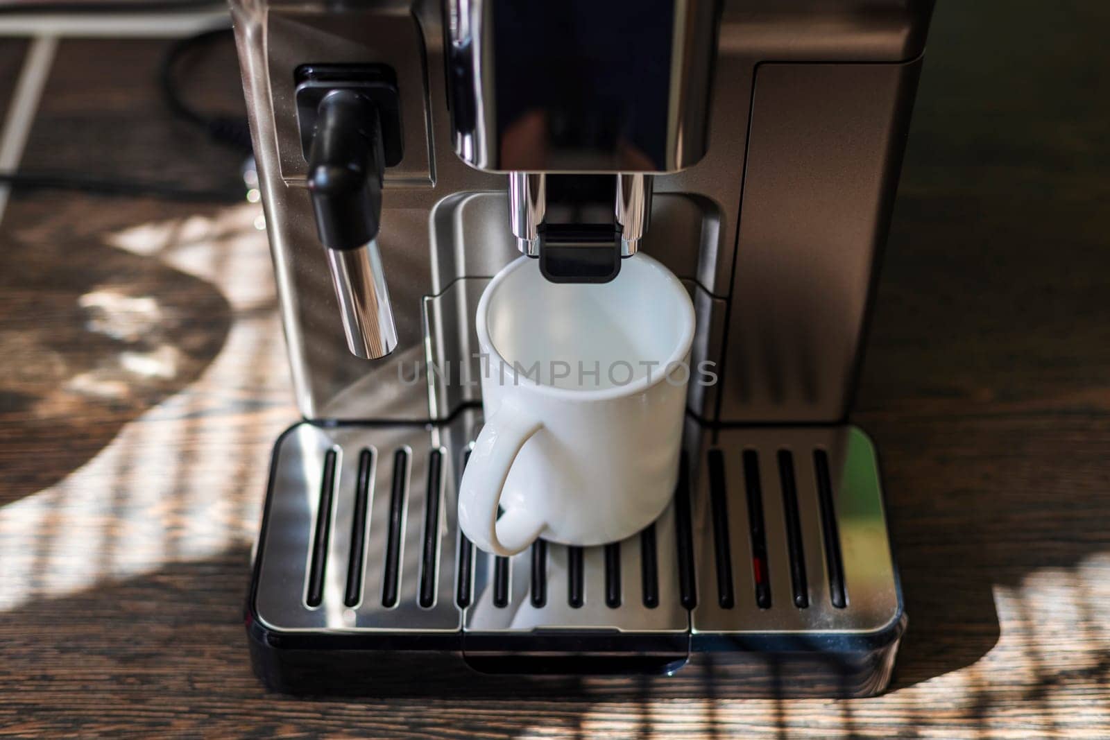 A sleek espresso machine fills a white mug with fresh coffee in a home setting.
