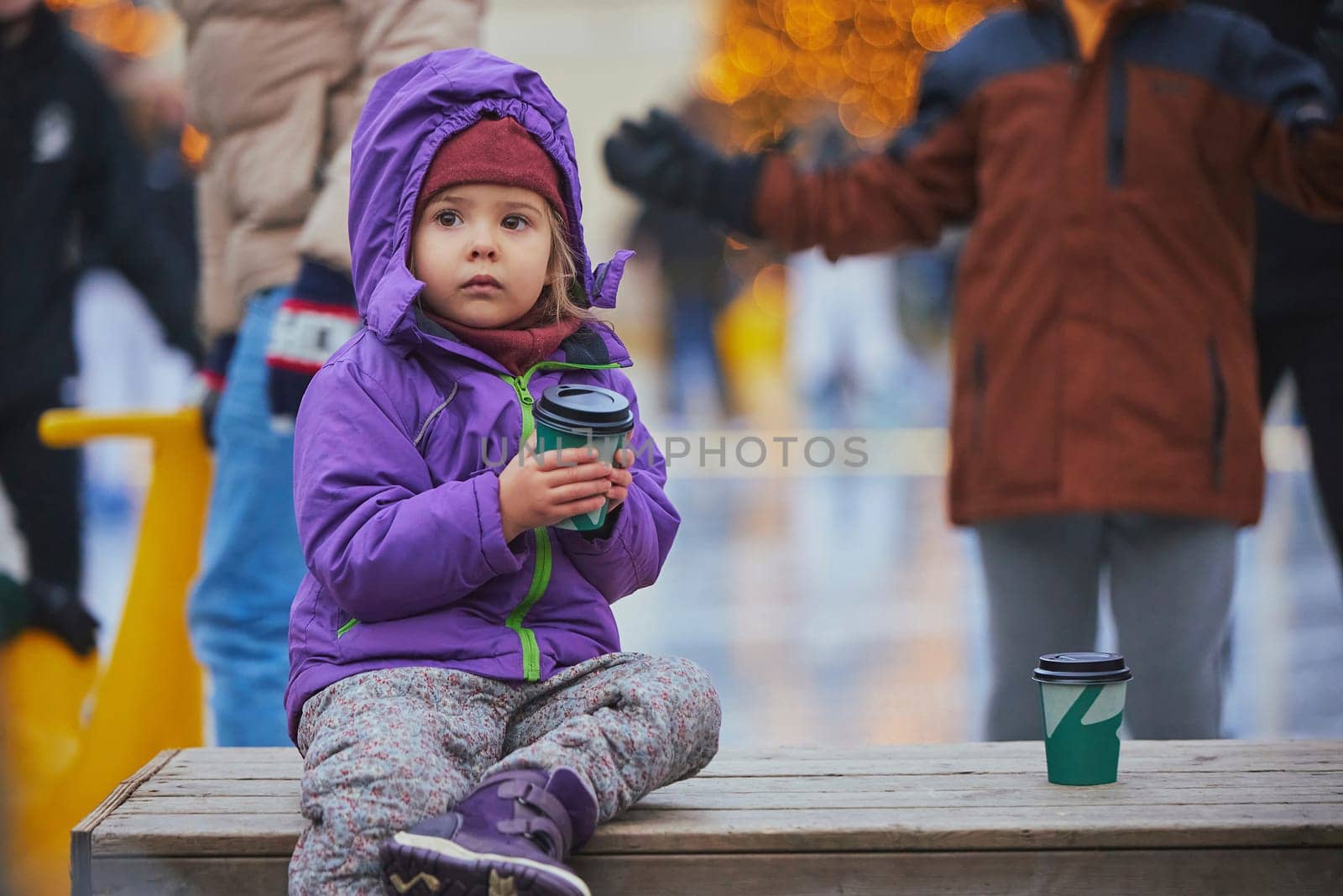 Charming child drinking coffee on the skating rink in Denmark.