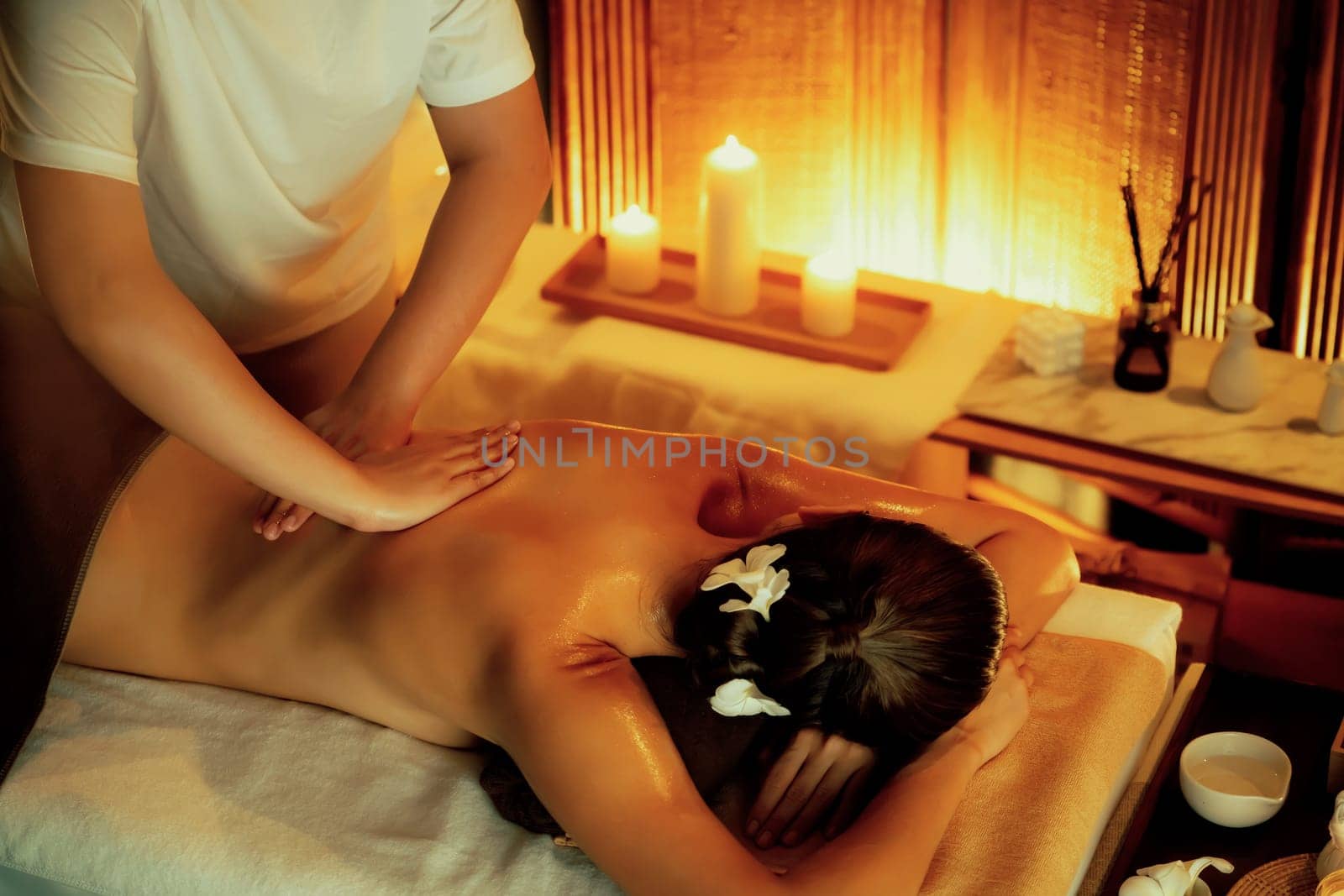 Caucasian woman customer enjoying relaxing anti-stress spa massage and pampering with beauty skin recreation leisure in warm candle lighting ambient salon spa at luxury resort or hotel. Quiescent