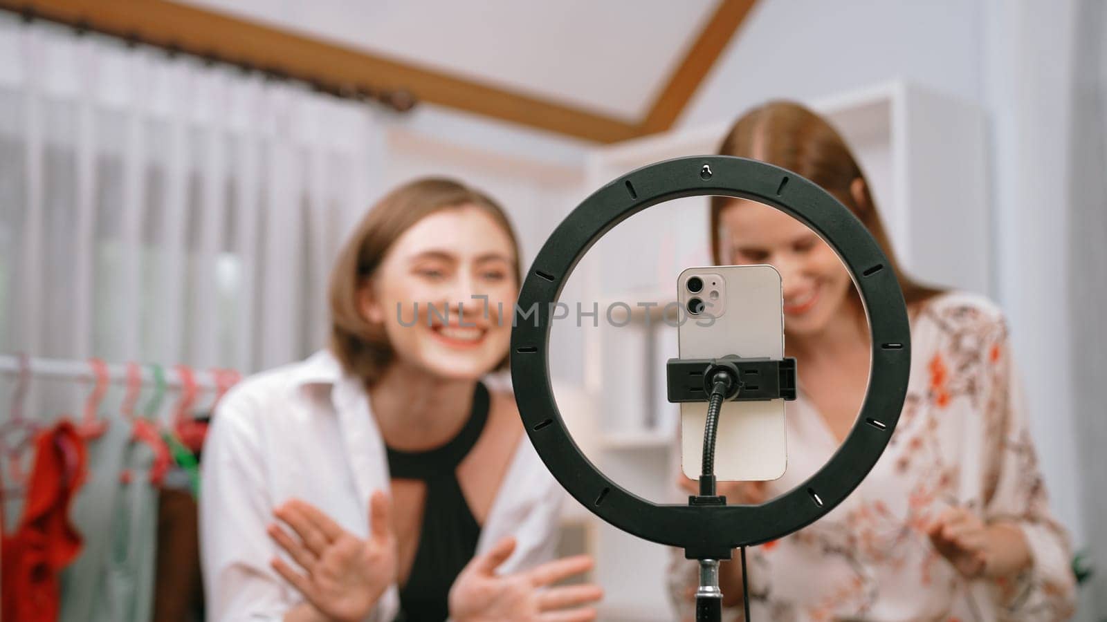 Two women influencer shoot live streaming vlog video review clothes prim social media or blog. Happy young girl with apparel studio lighting for marketing recording session broadcasting online.