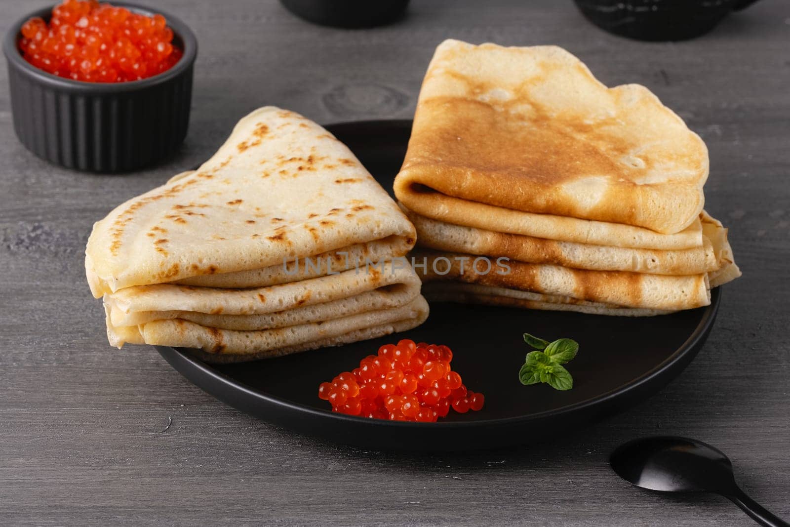 Pancakes with red caviar. Close-up of pancakes stacked on grey background.