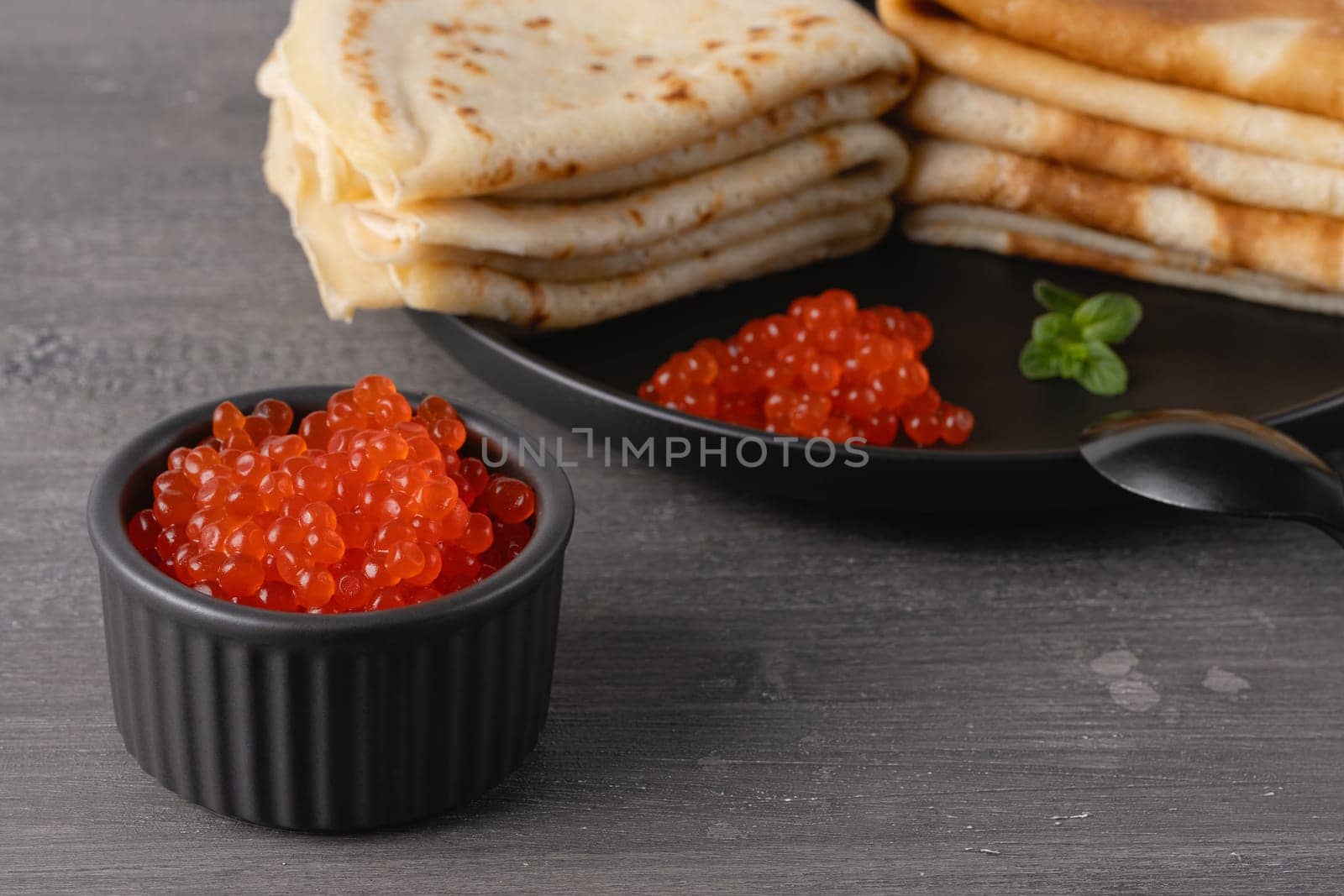 Pancakes with red caviar. Close-up of pancakes stacked on grey background.