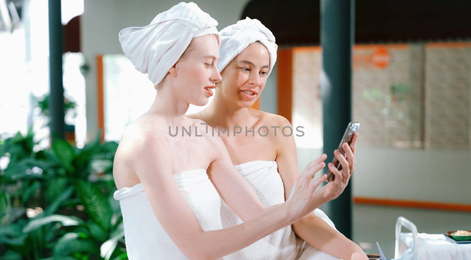 Couple of young beautiful women with beautiful skin in white towel taking a photo together at outdoor surrounded by peaceful natural environment. Beauty and healthy spa concept. Tranquility.