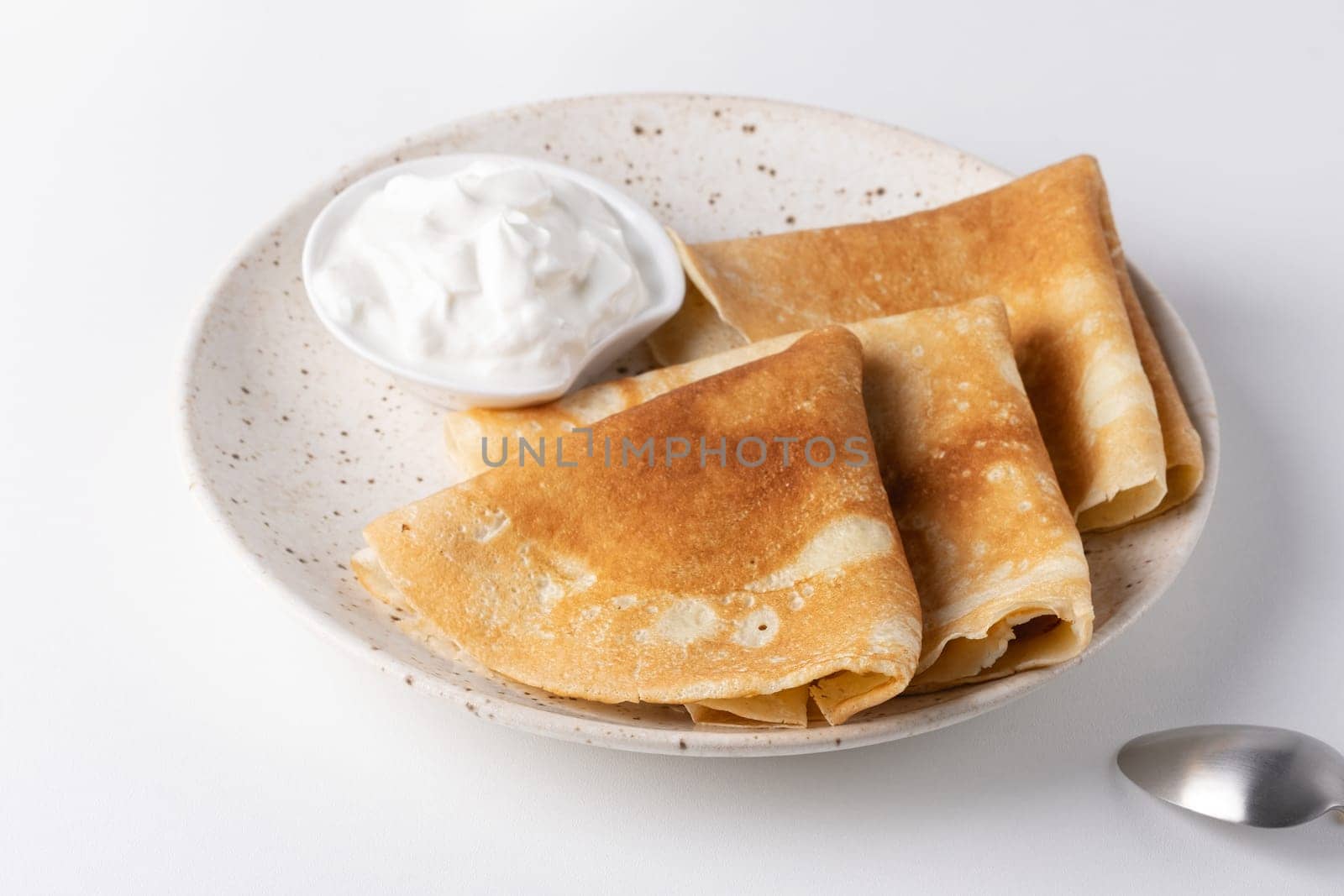 Stack of russian thin pancakes blini with fresh sour cream.