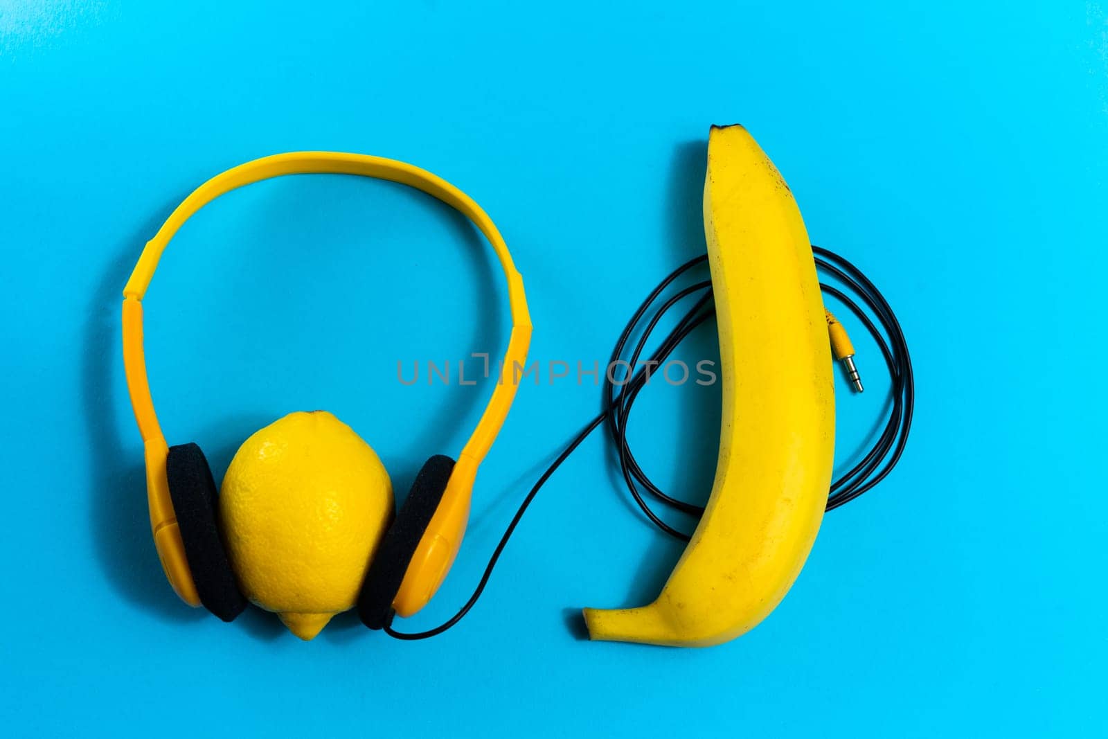 Minimalism flat lay concept, listens to a music. Headphones, banana on blue background. Top view