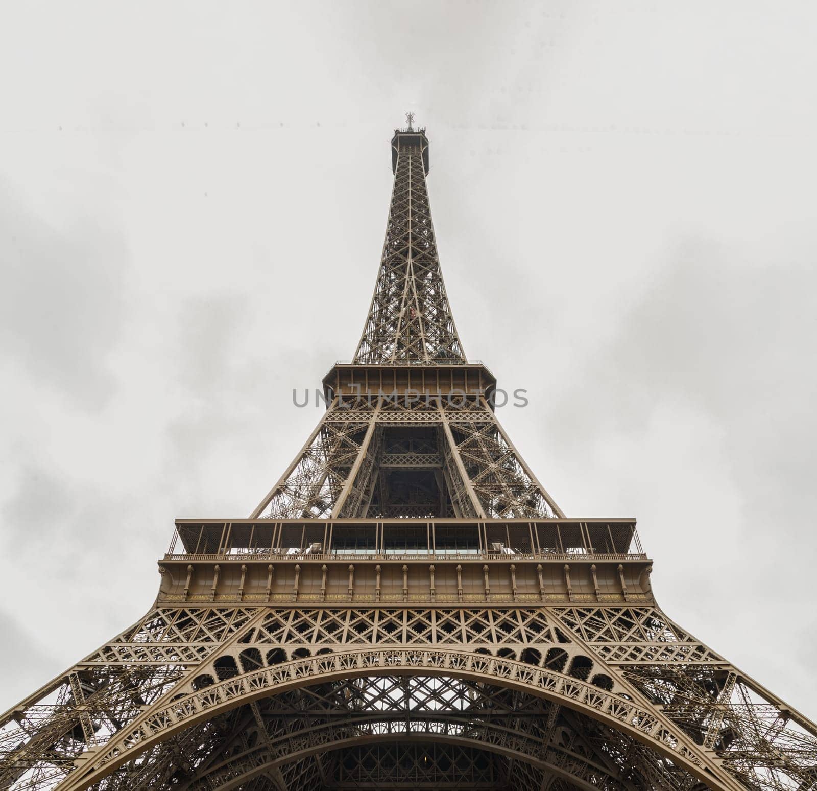 France, Paris - Jan 4, 2024 - Low angle shot of Famous Eiffel tower iron structure with white sky background. Architectural detail design of the Eiffel tower in Paris. Paris Best Destinations in Europe, Space for text, Selective focus.