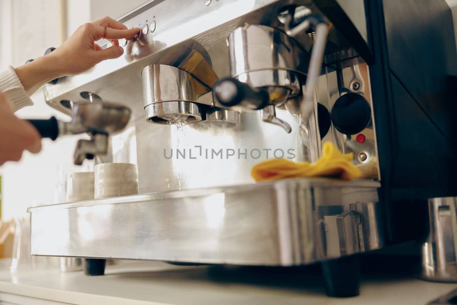 Close up of female barista making coffee in a coffee machine while working in cafe by Yaroslav_astakhov