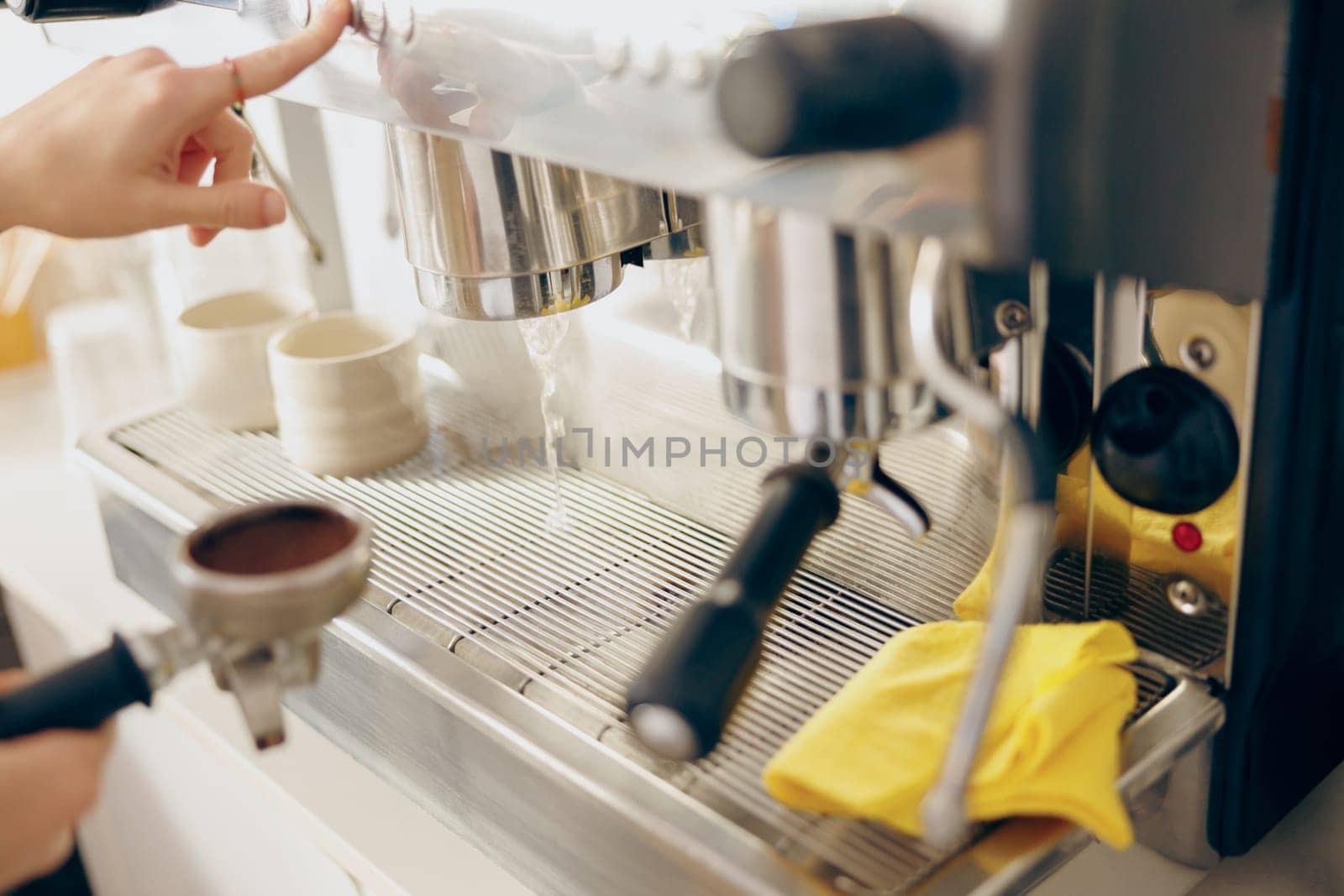 Close up of female barista making coffee in a coffee machine while working in cafe