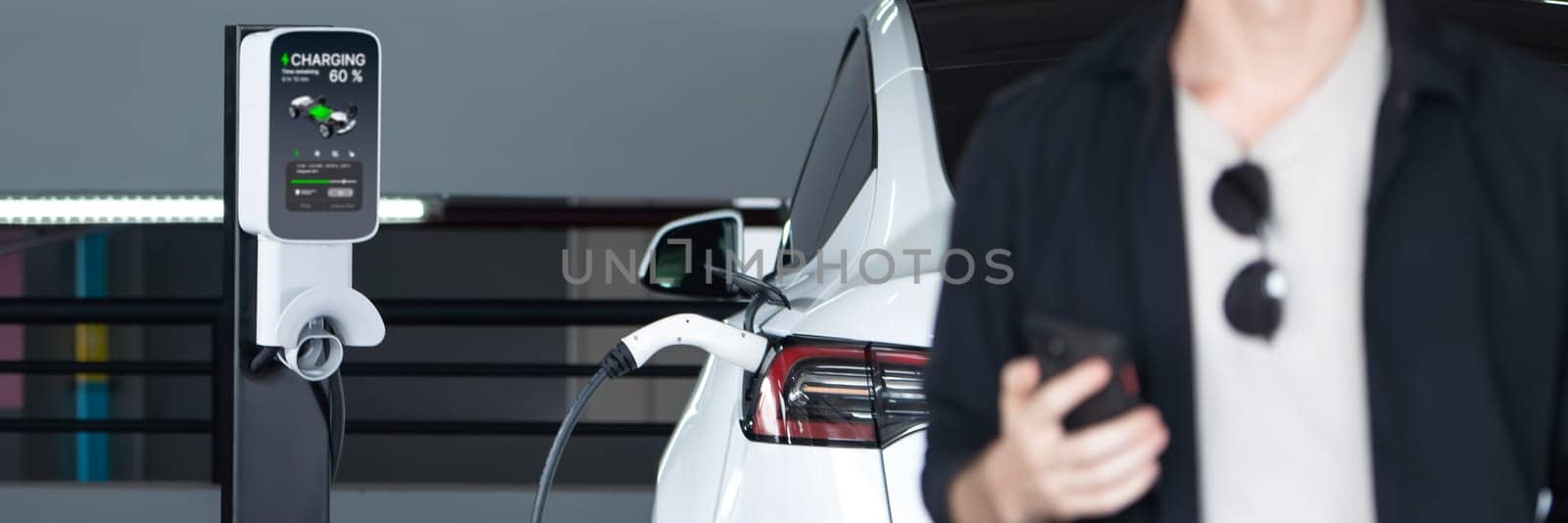 Young man travel with EV electric car to shopping center parking lot innards by biancoblue