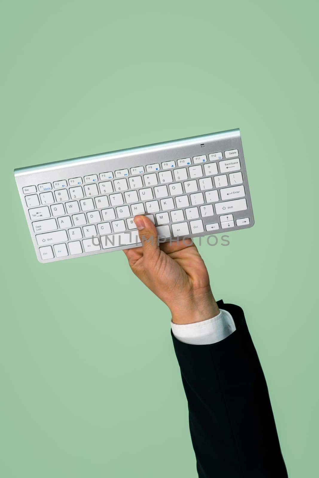 Hand holding wireless keyboard on isolated background for start up tech company. Eco-friendly green business promoting electronic waste policy idea. Quaint