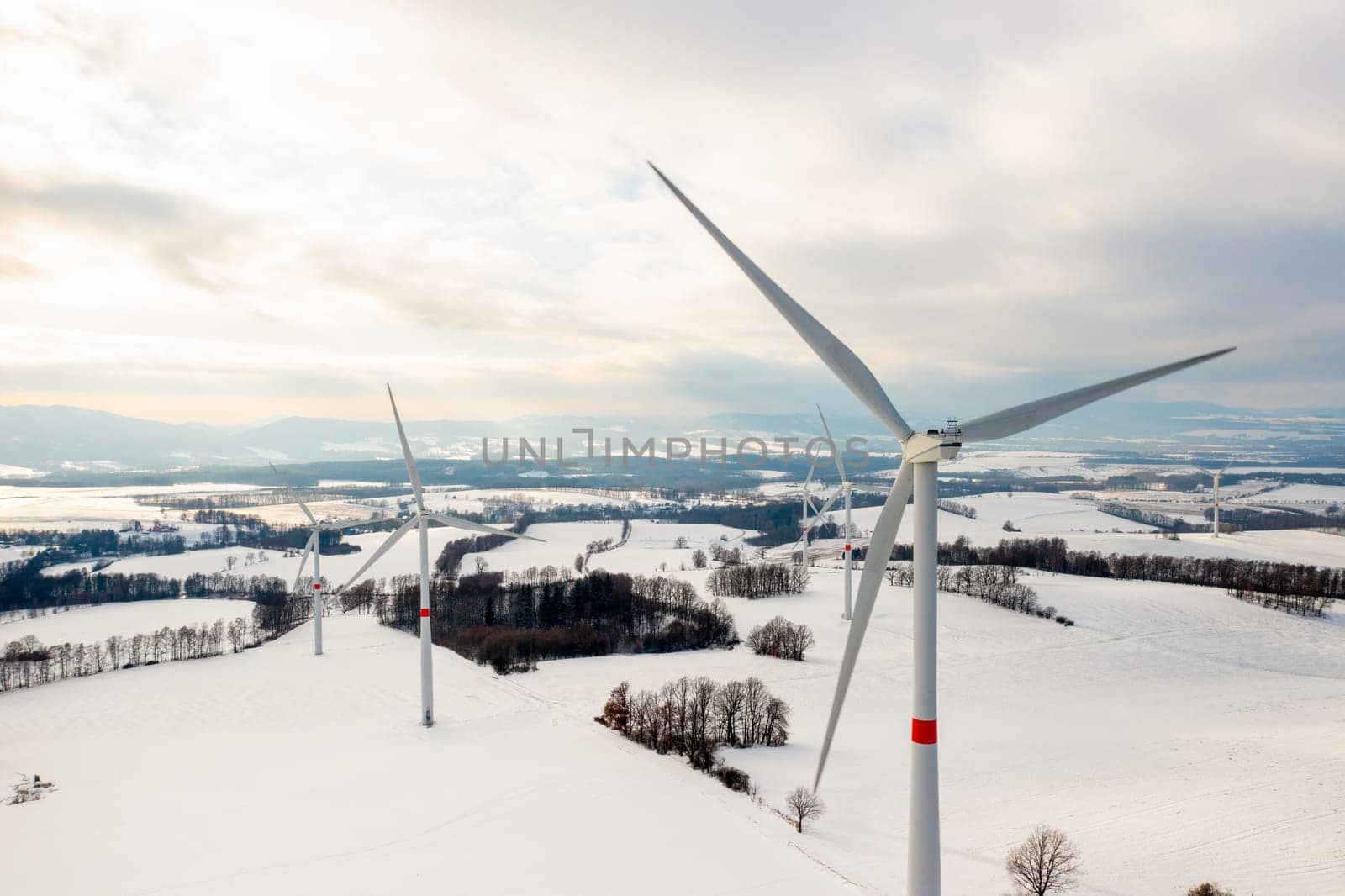 Windmill park or wind turbines in the winter field at sunset. Production of clean energy