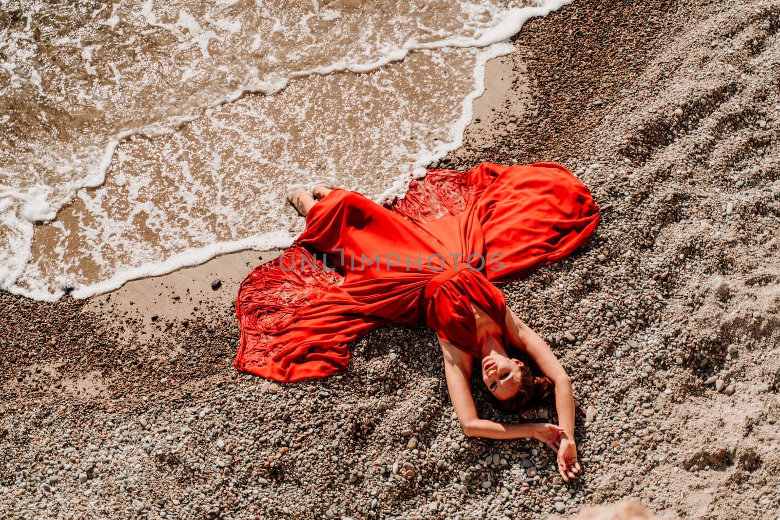 Woman red dress sea. Female dancer in a long red dress posing on a beach with rocks on sunny day by Matiunina