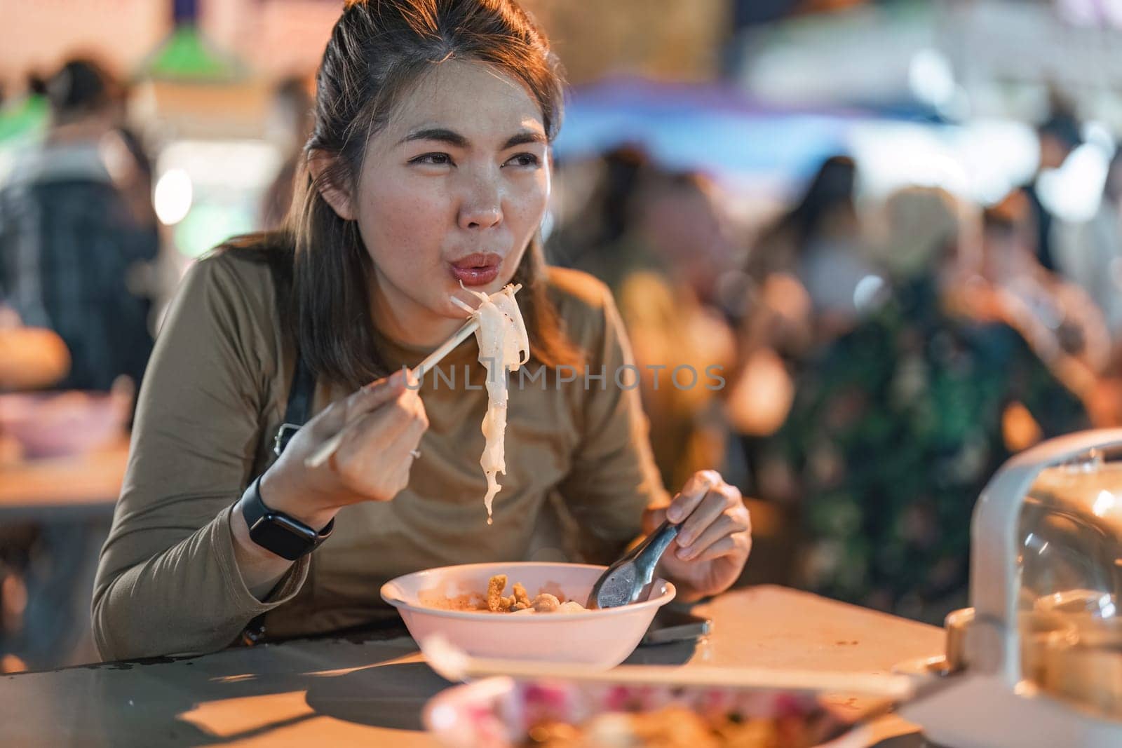 Traveler Asian woman enjoy eating noodle at night market. traditional Chiang Mai Thailand street food. by nateemee