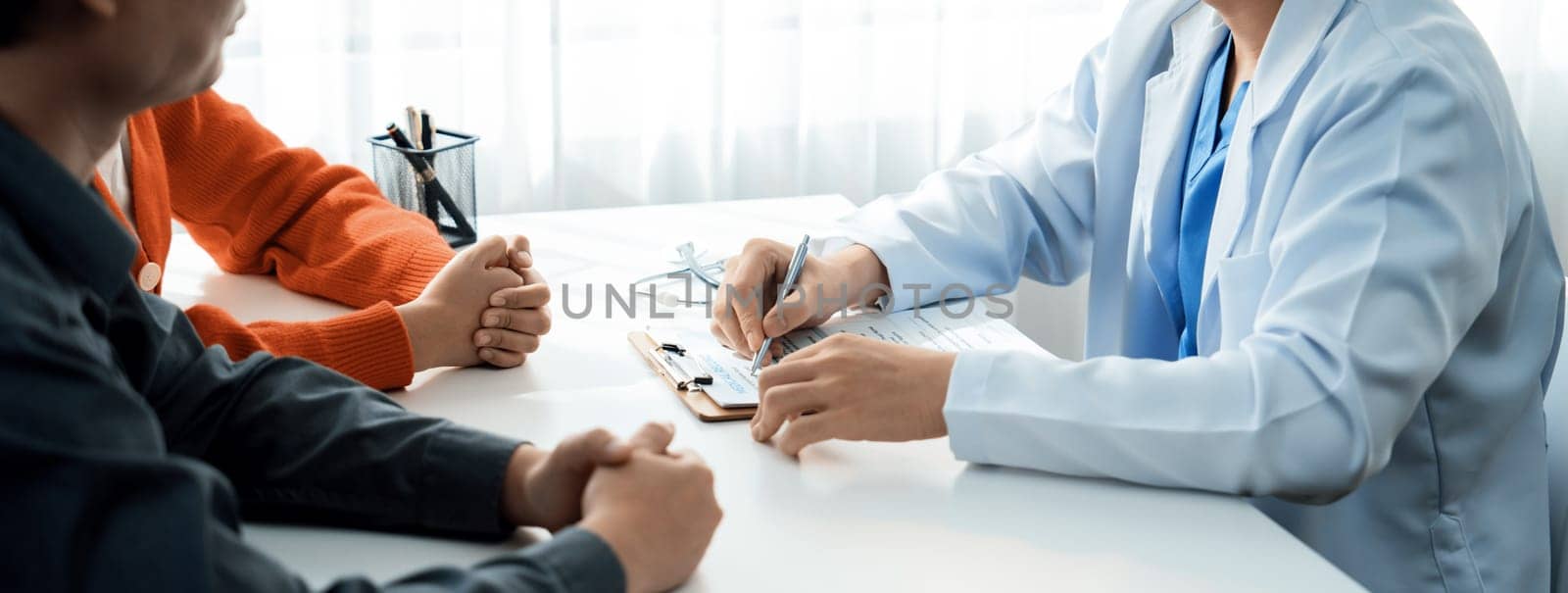 Couple attend fertility consultation with gynecologist at hospital as part family planning care for pregnancy. Loving husband and wife support each other through the doctor appointment. Panorama Rigid